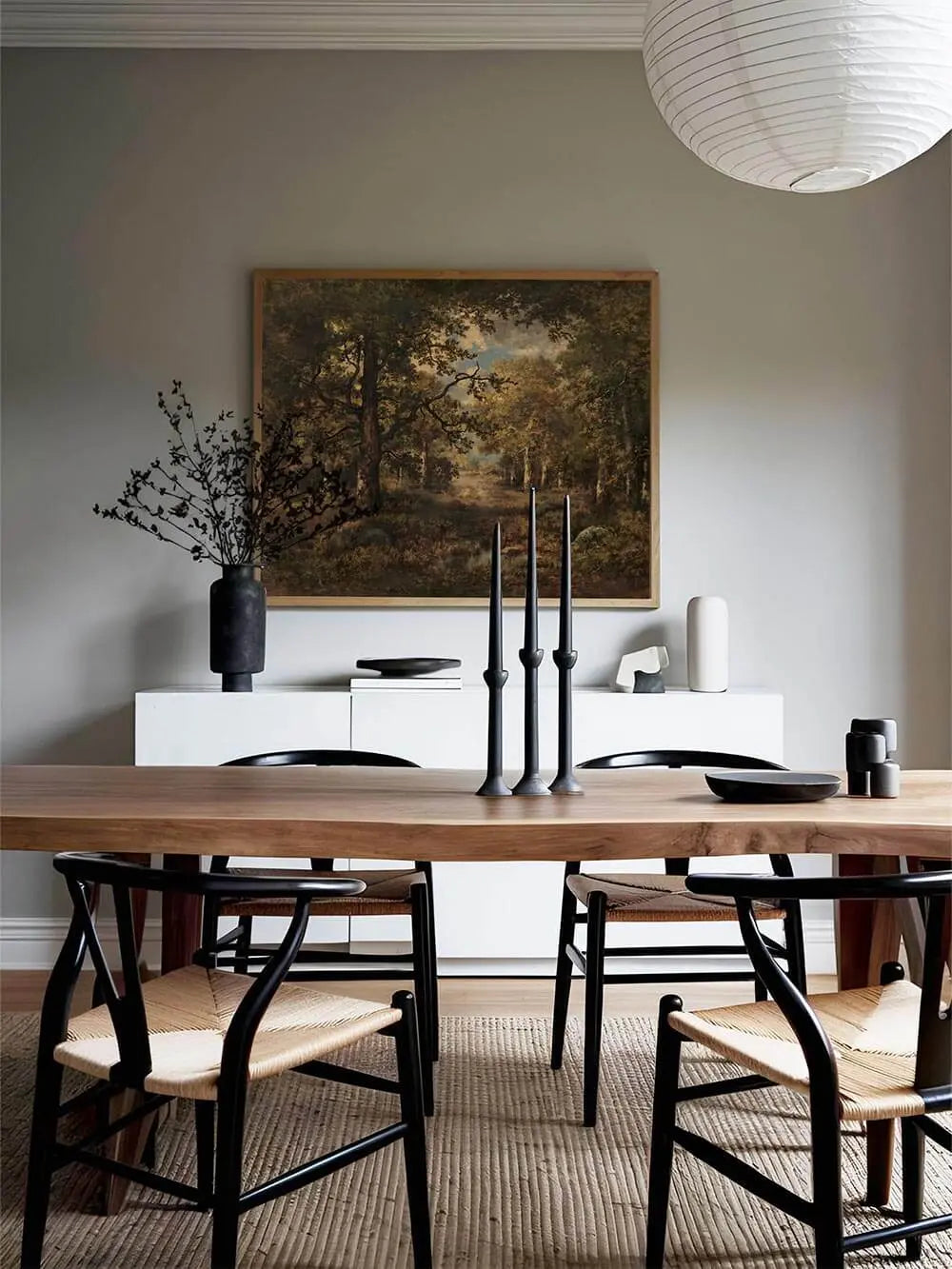 Gerahmter Kunstdruck einer Waldlandschaft hängt über einem modernen Holztisch. Das Bild verleiht dem Esszimmer eine warme, nostalgische Atmosphäre.