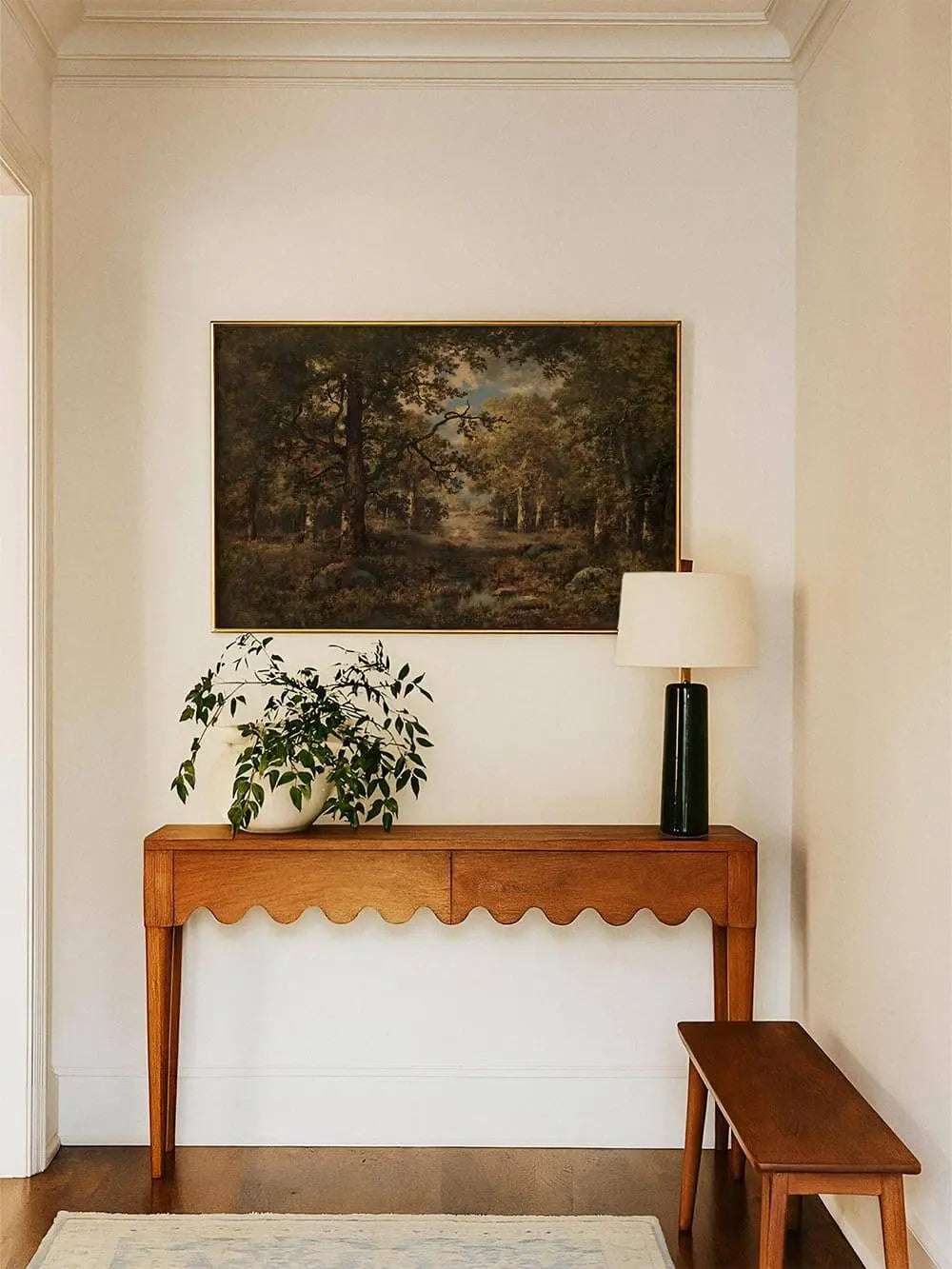 Der dunkle Waldlandschaft Kunstdruck hängt gerahmt über einer schmalen Konsole mit Tischlampe. Das Wandbild bringt Tiefe und Eleganz in den Flur.