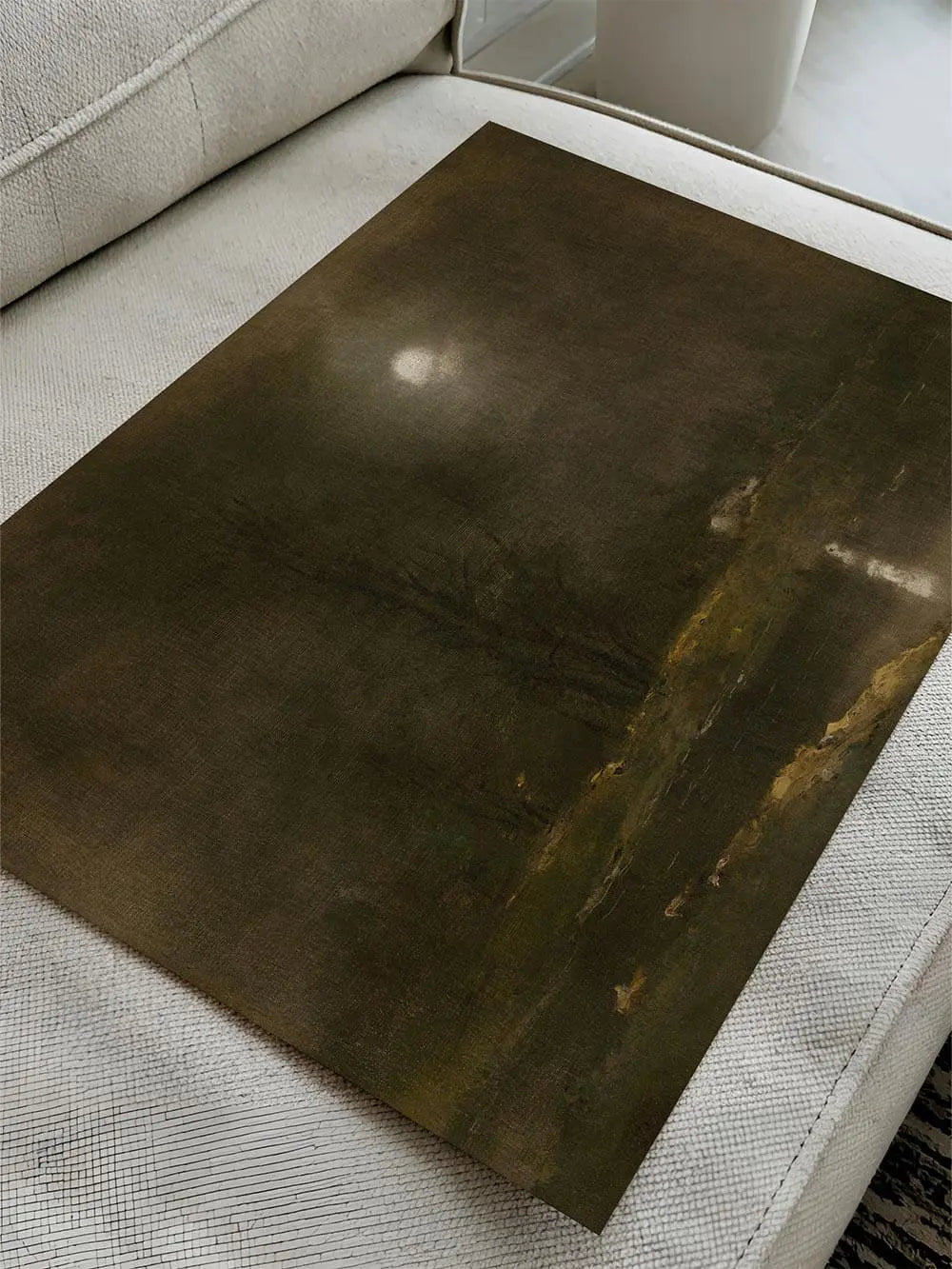 Kunstdruck einer dunklen Nachtlandschaft mit hellem Mond liegt ungerahmt auf einem Sofa. Die gedeckten Farben und die sichtbare Leinwandstruktur verleihen ihm Tiefe.