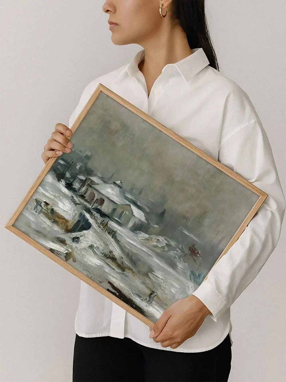 Eine Person hält den gerahmten Winterlandschaft Kunstdruck vor sich. Die verschneite Szene mit Häusern wirkt ruhig und zeitlos.