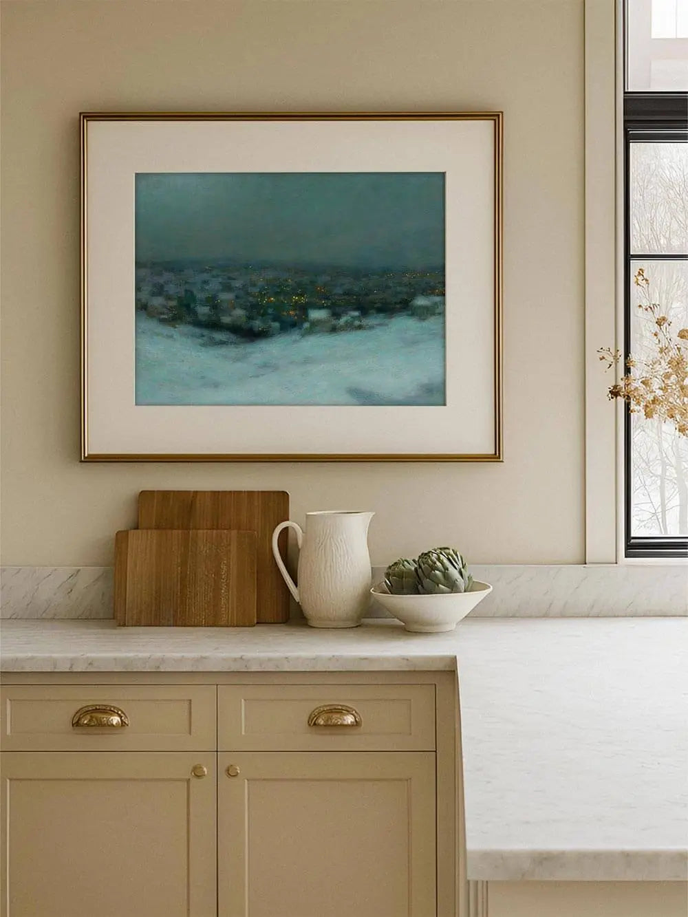 Winterlandschaft Kunstdruck mit blauen und grauen Tönen hängt gerahmt in einer hellen Küche, die goldenen Lichtpunkte setzen warme Akzente in der kühlen Szenerie.