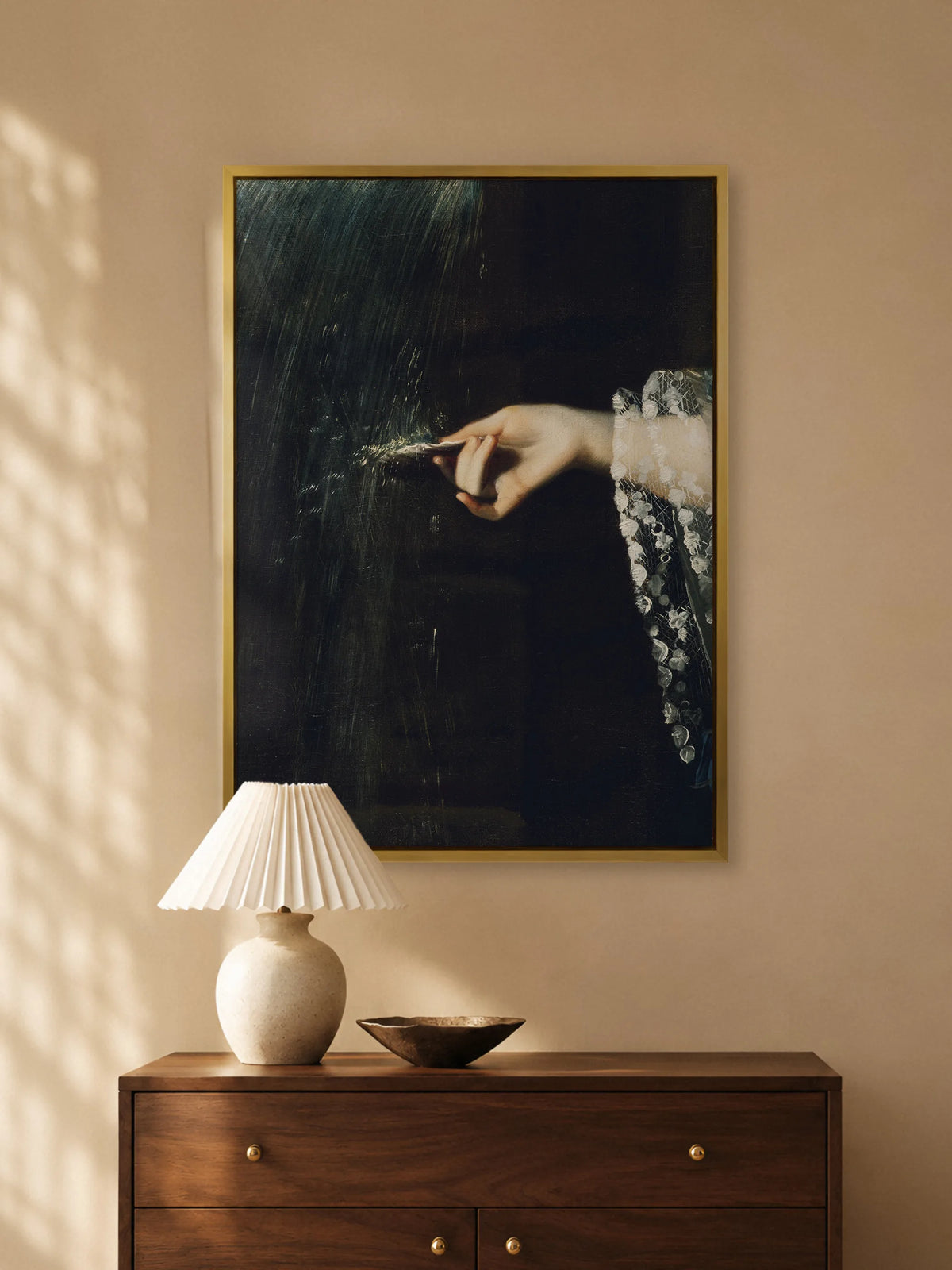 Leinwandbild mit Hand und Muschel im goldenen Rahmen über einer Kommode aus Nussbaum mit plissierter Tischlampe aus Keramik und Schale