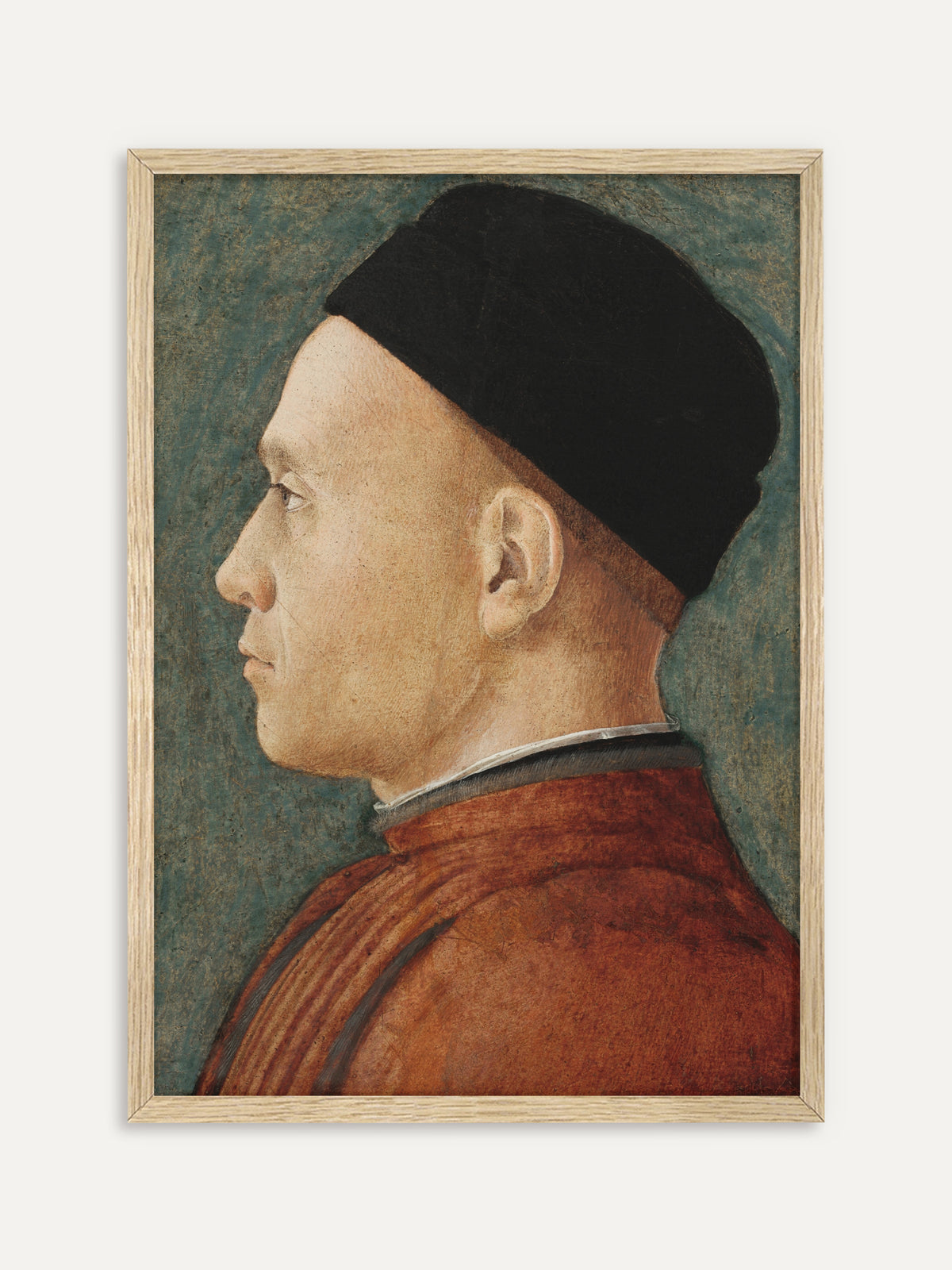 Kunstdruck, der einen Mann im Profil zeigt, der eine schwarze Kappe und ein rostrotes Gewand mit hohem Kragen trägt, vor einem fleckigen blaugrünen Hintergrund. Im Rahmen aus hellem Holz wirkt das Renaissance-Porträt ruhig und hell. #Rahmen_Helles Holz