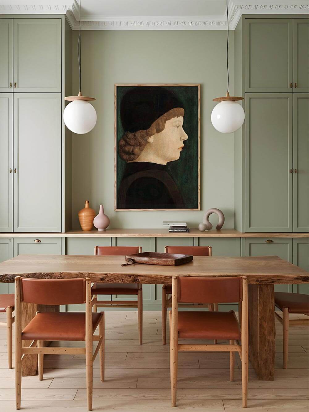 Renaissance-Porträt-Kunstdruck in modernem Esszimmer mit grünen Schrankfronten. Das klassische Profilbild fügt sich harmonisch in elegante, zeitlose Interieurs ein.