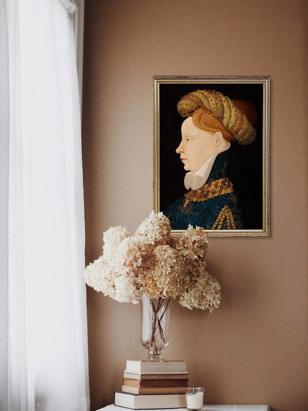 Gerahmter Renaissance-Kunstdruck einer Frau im Profil hängt über einem Tisch mit hellen Trockenblumen und Büchern. Warme Lichtstimmung und klassische Eleganz schaffen ein harmonisches, historisch inspiriertes Ambiente.