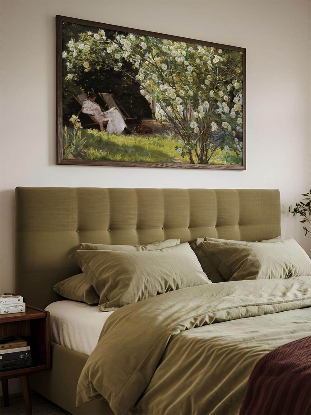 Elegantes Vintage-Gartenposter über einem Bett mit olivgrüner Bettwäsche. Der impressionistische Kunstdruck zeigt eine Frau in einem Liegestuhl unter einem blühenden Rosenstrauch. Sanftes Sonnenlicht schafft eine idyllische, beruhigende Atmosphäre.