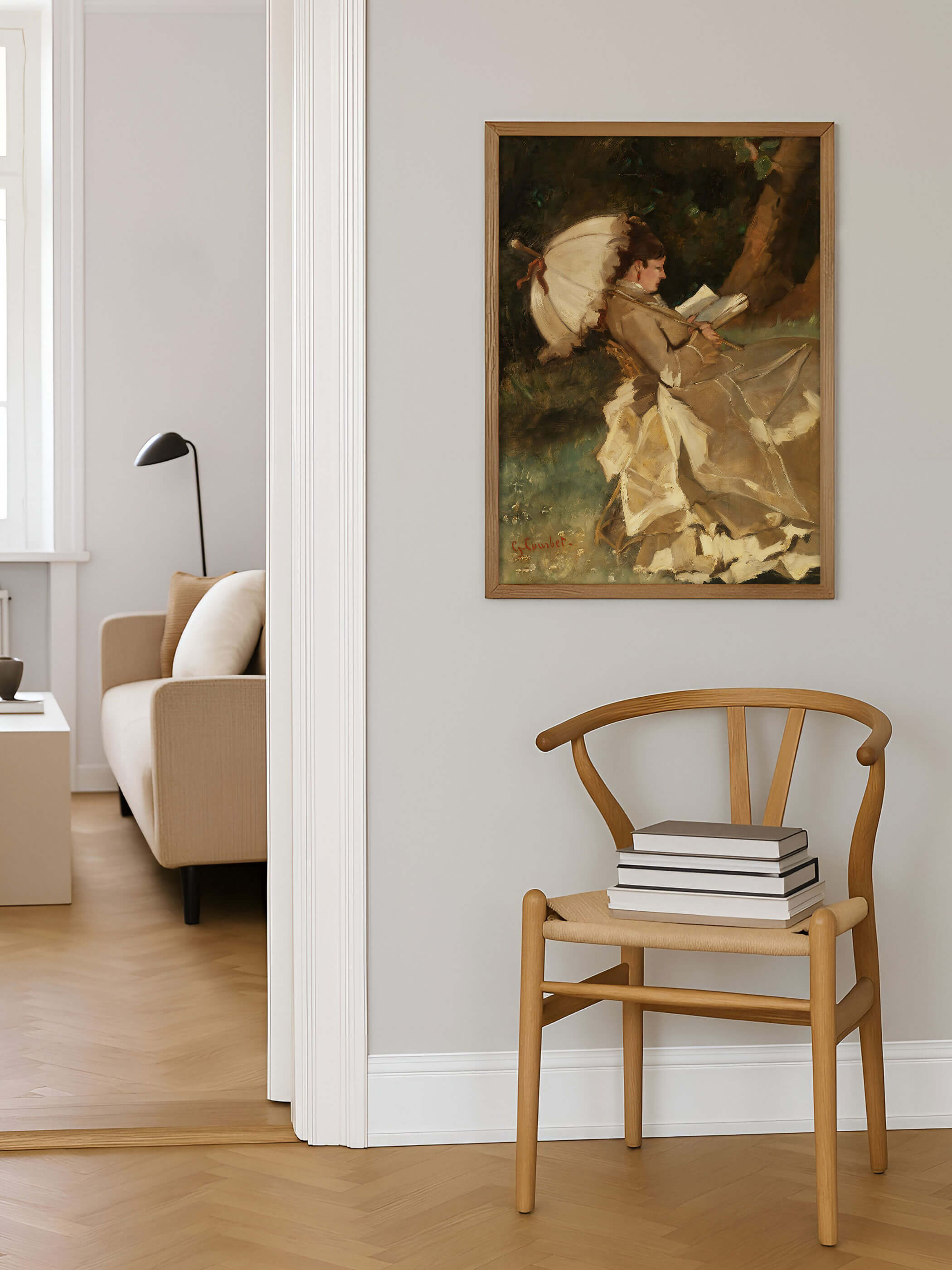 Gerahmter Kunstdruck mit impressionistischem Motiv einer lesenden Frau im Garten, aufgehängt über einem Holzstuhl in hellem Wohnraum mit Parkettboden und neutraler Wandfarbe, als stilvolles Wandbild für klassische und moderne Einrichtungen.