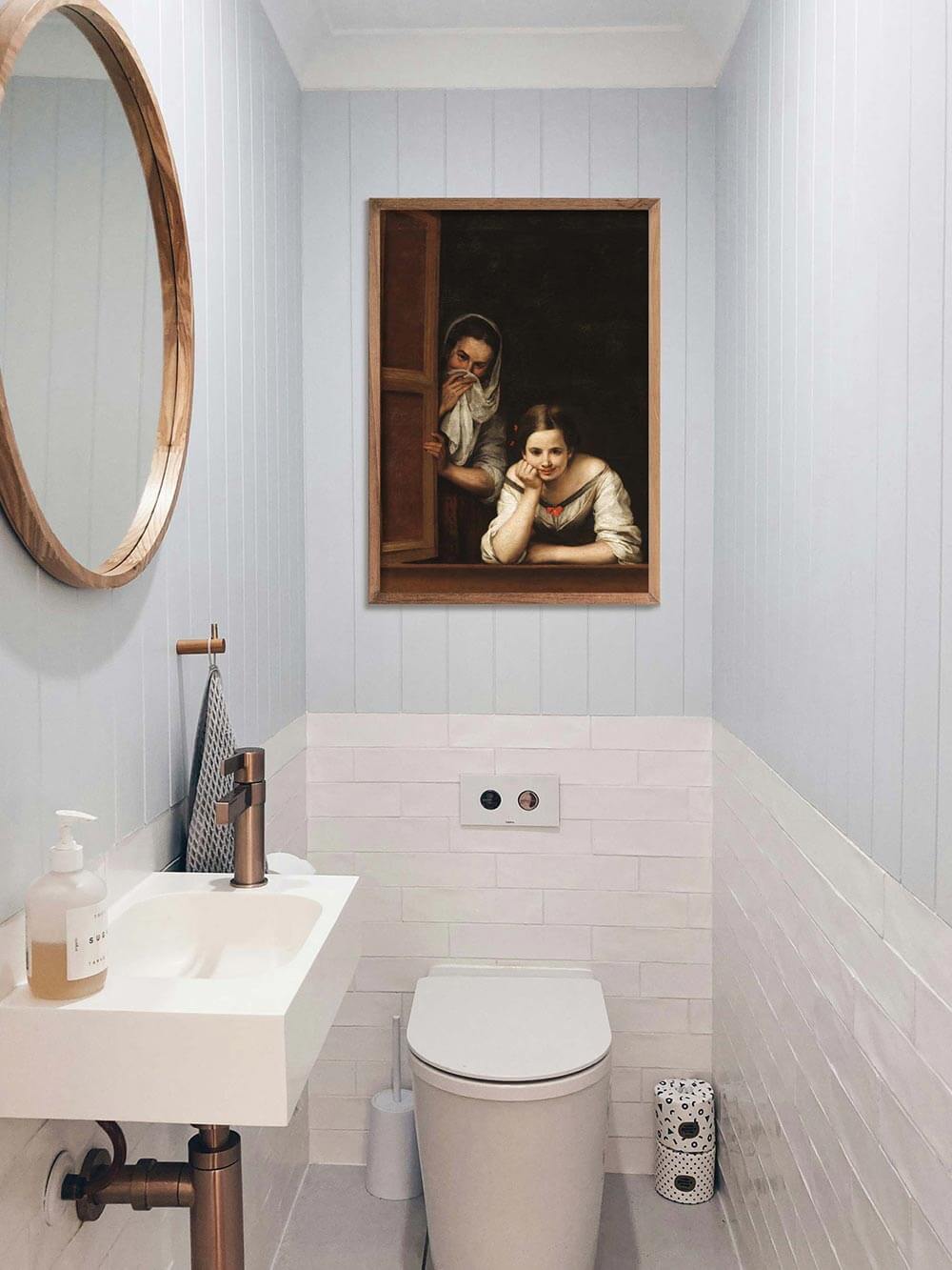Der Kunstdruck hängt gerahmt über einem Waschbecken in einem modernen Badezimmer. Die heitere Szene bringt Leichtigkeit und Humor  in den reduzierten Raum.