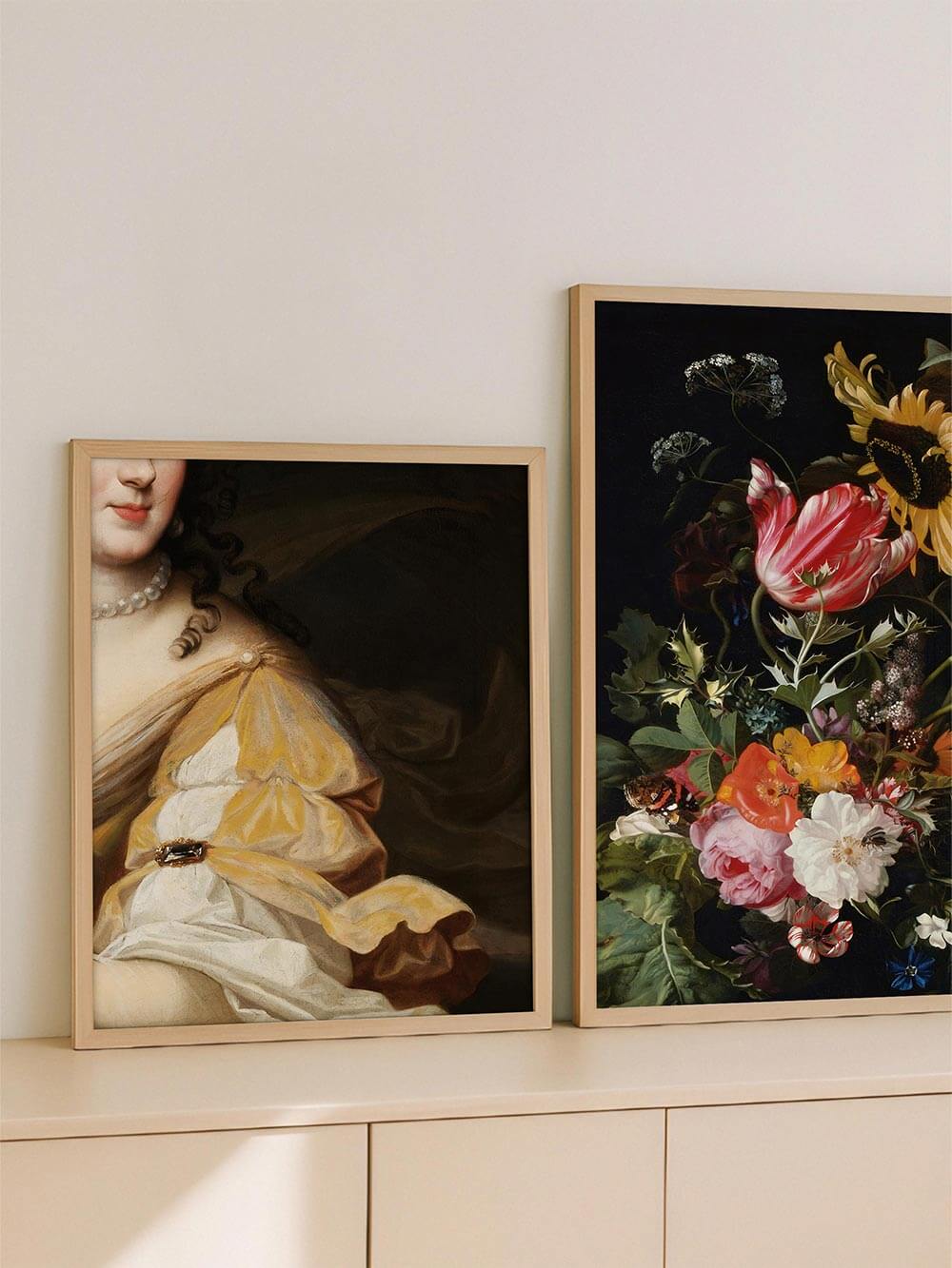 Barockes Damenporträt in harmonischer Kombination mit floralem Stillleben – zwei Kunstdrucke in Holzrahmen auf einem Sideboard vor heller Wand, dekorativ arrangiert.