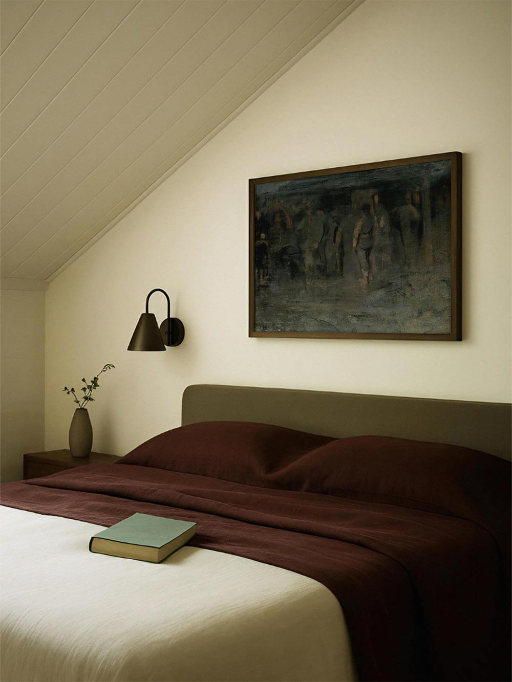 Dunkler, atmosphärischer Kunstdruck mit schemenhaften Figuren hängt über einem Bett in einem ruhig gestalteten Schlafzimmer mit warmen Textilien. Das Wandbild in gedeckten Grün- und Brauntönen wirkt still und introspektiv und passt zu moody Interior, Dark Academia und minimalistischer Wanddekoration.