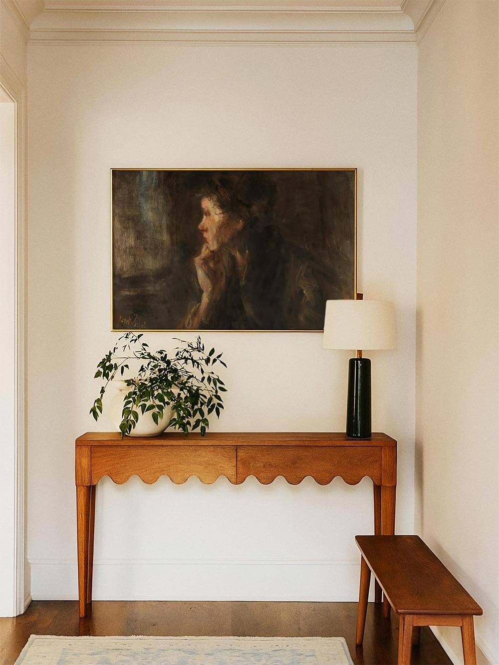 Dunkles Frauenporträt als Kunstdruck in einem hellen Flur über einer schmalen Konsole arrangiert. Das moody Wandbild setzt einen stillen, kunstvollen Akzent und schafft einen eleganten ersten Eindruck.