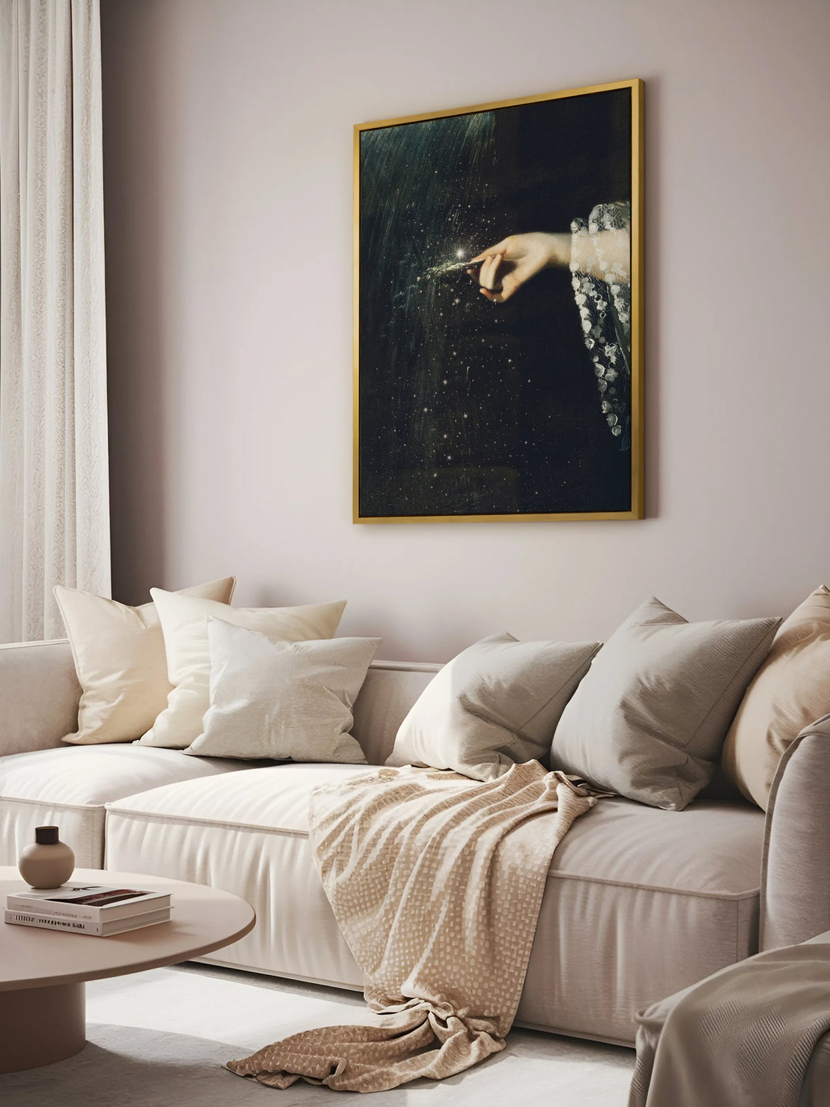 Leinwandbild mit Hand und Sternen im goldenen Rahmen über einem cremefarbenen Sofa mit Kissen, Strickdecke und rundem Couchtisch im Wohnzimmer