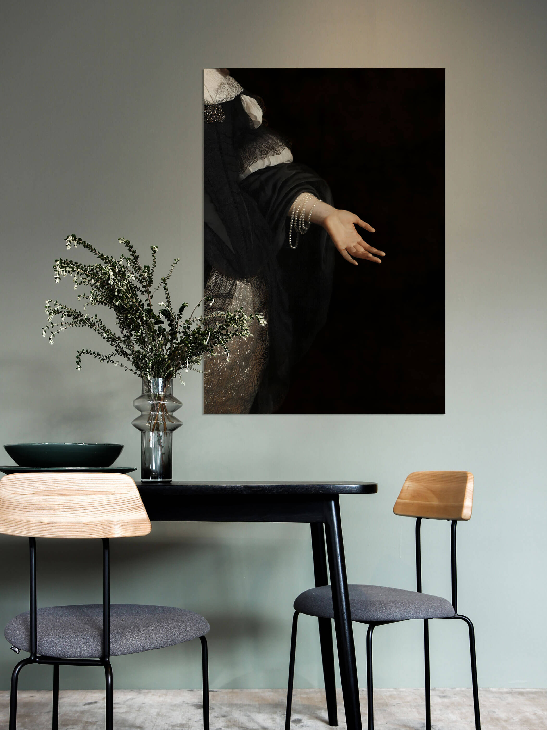Nahaufnahme eines klassischen Gemäldes, das eine elegante, leicht ausgestreckte Hand in schwarzem Stoff mit Perlenschmuck zeigt, auf dunklem Hintergrund aufgehängt im Esszimmer.