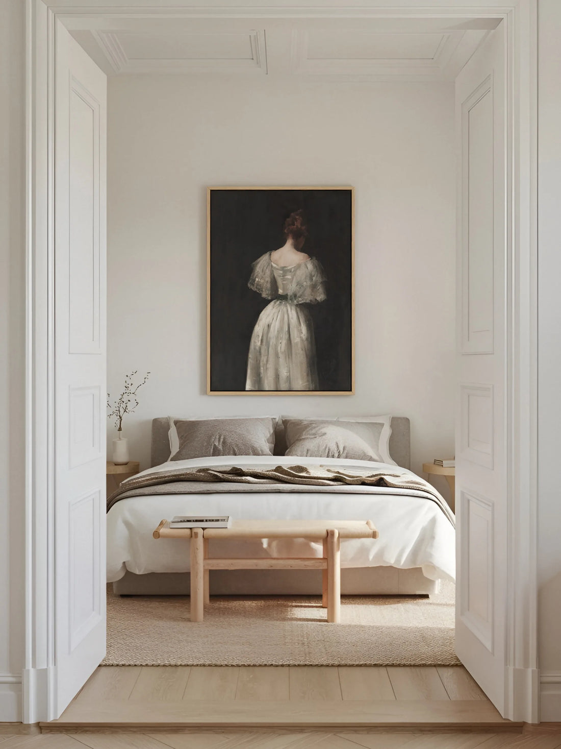 Leinwandbild einer Frau im weißen Kleid im naturfarbenen Rahmen über einem Bett mit grauer Bettwäsche im hellen Altbau Schlafzimmer mit Holzbank