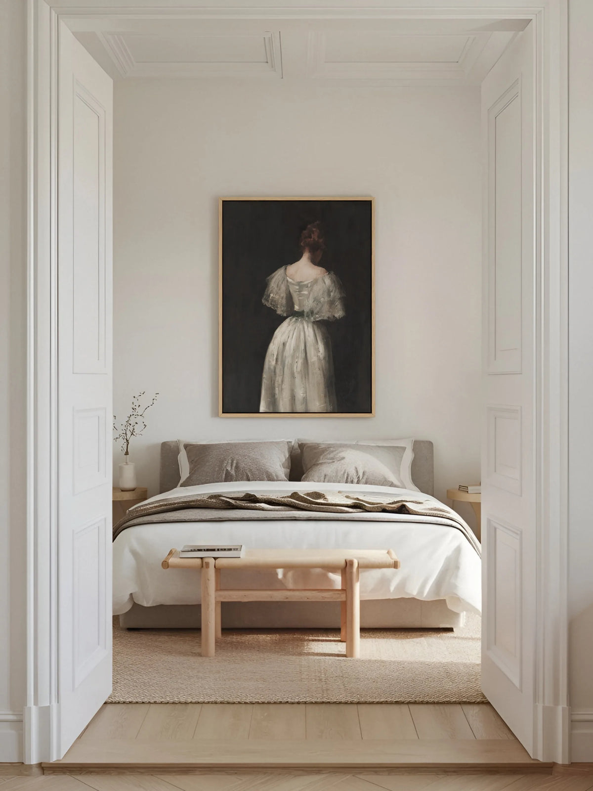 Leinwandbild einer Frau im weißen Kleid im naturfarbenen Rahmen über einem Bett mit grauer Bettwäsche im hellen Altbau Schlafzimmer mit Holzbank