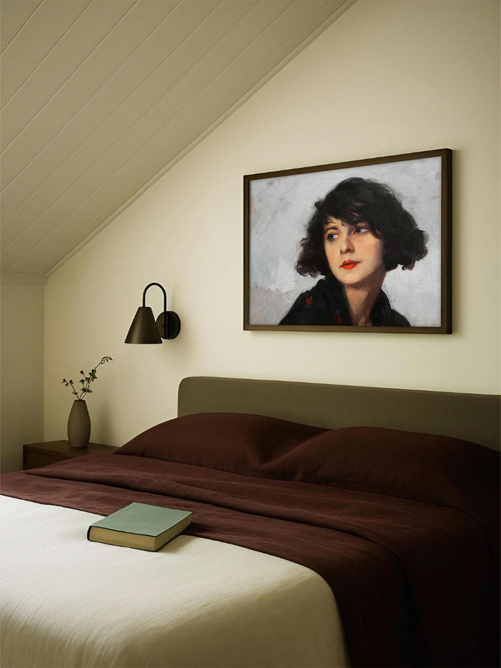 Gerahmter Kunstdruck eines expressiven Frauenporträts mit dunklem Haar und rotem Lippenstift über einem Bett mit brauner Decke; sanfte Lichtstimmung und moderne Schlafzimmergestaltung.