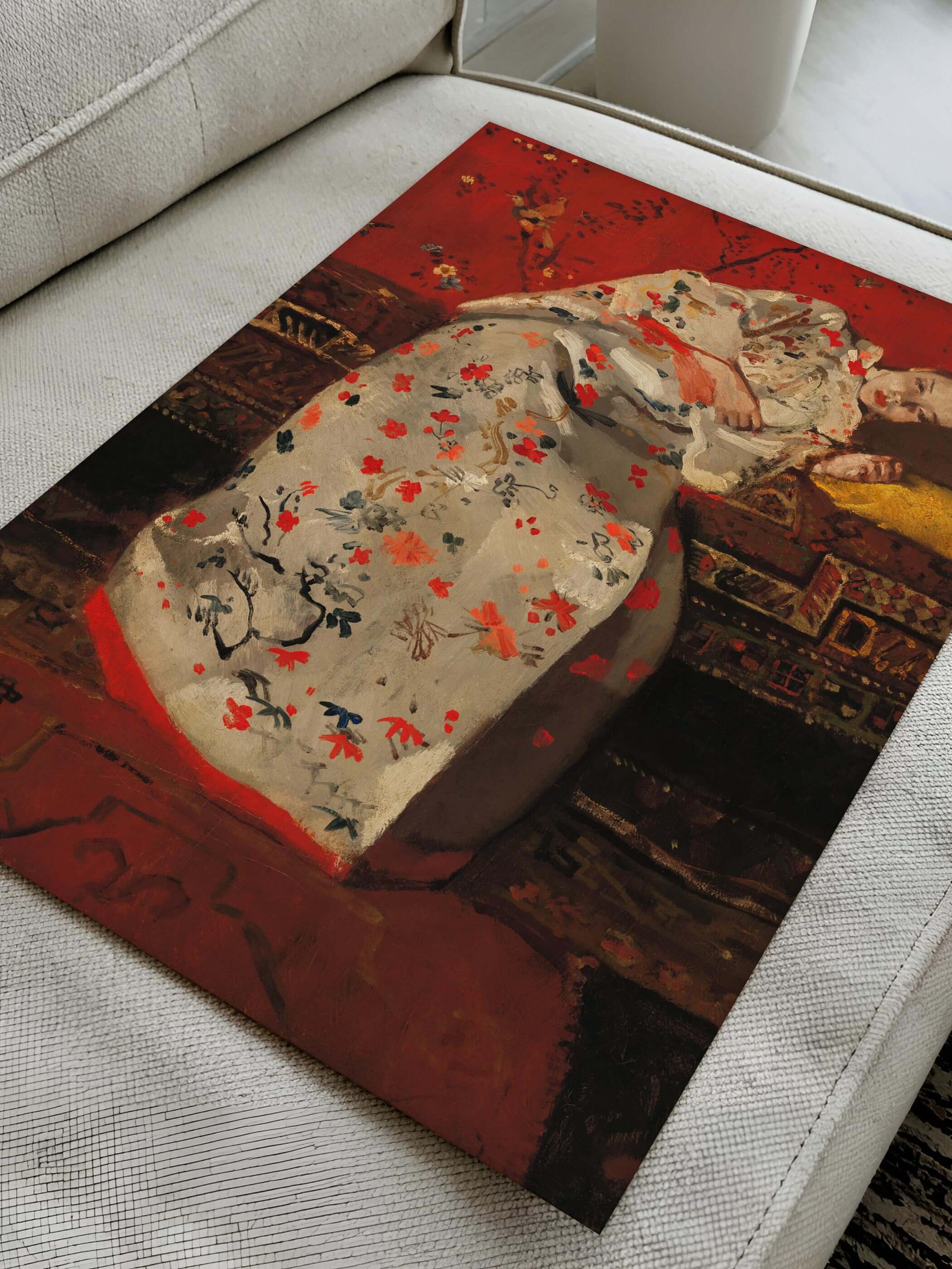 Ein Poster des Gemäldes „Girl in White Kimono“ von George Hendrik Breitner, auf einem Sofa liegend. Der weiße Kimono mit floralen Mustern steht im Kontrast zum intensiven Rot des Hintergrunds. Ideal für klassische und moderne Wohnräume.