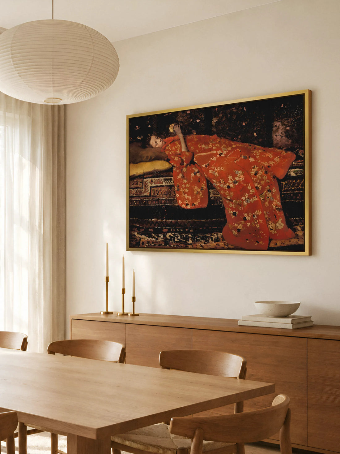 Großes Leinwandbild mit Frau im roten Kimono im goldenen Rahmen über einem Sideboard aus warmem Holz im Esszimmer. Darauf stehen drei Messingleuchter mit Kerzen und eine Steinschale, davor ein Holztisch mit Stühlen.
