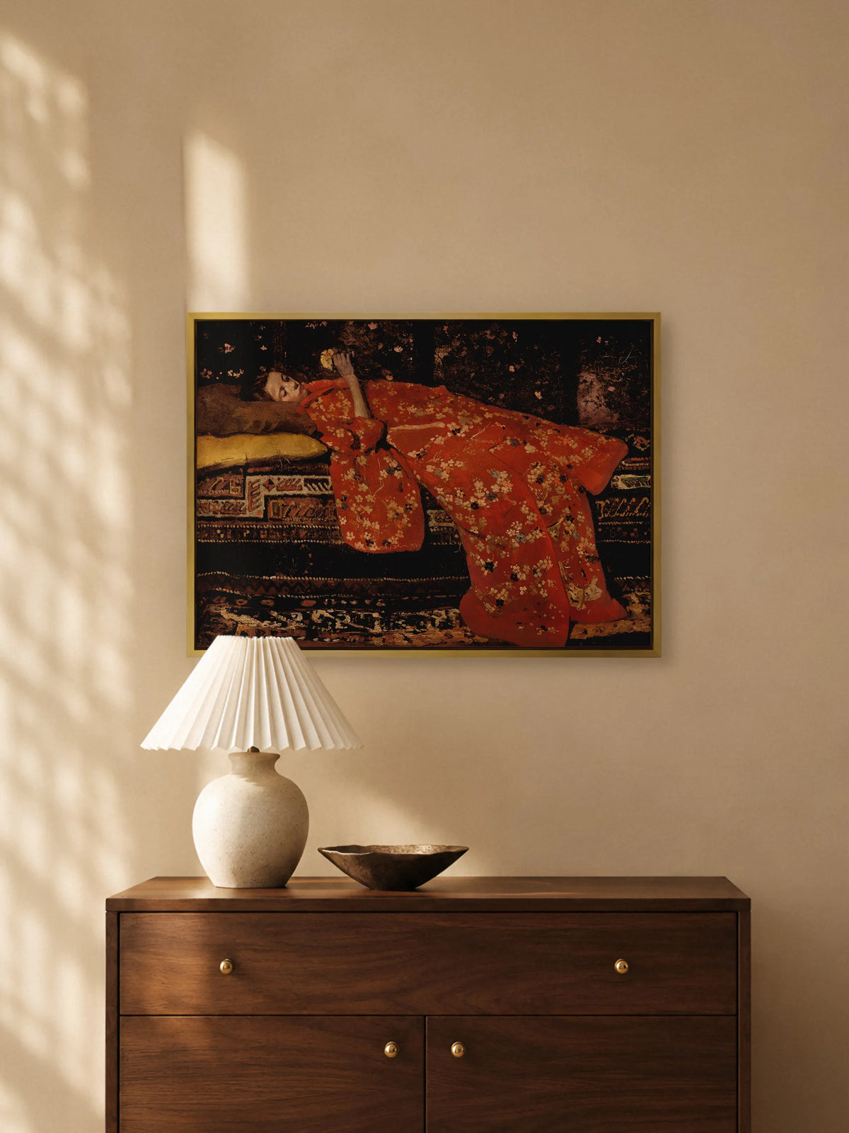 Porträt im roten Kimono als Leinwandbild im goldenen Rahmen über einer dunklen Holzkommode mit Messingknöpfen. Auf der Kommode stehen eine Keramiklampe mit weißem Plisseeschirm und eine flache Bronzeschale.