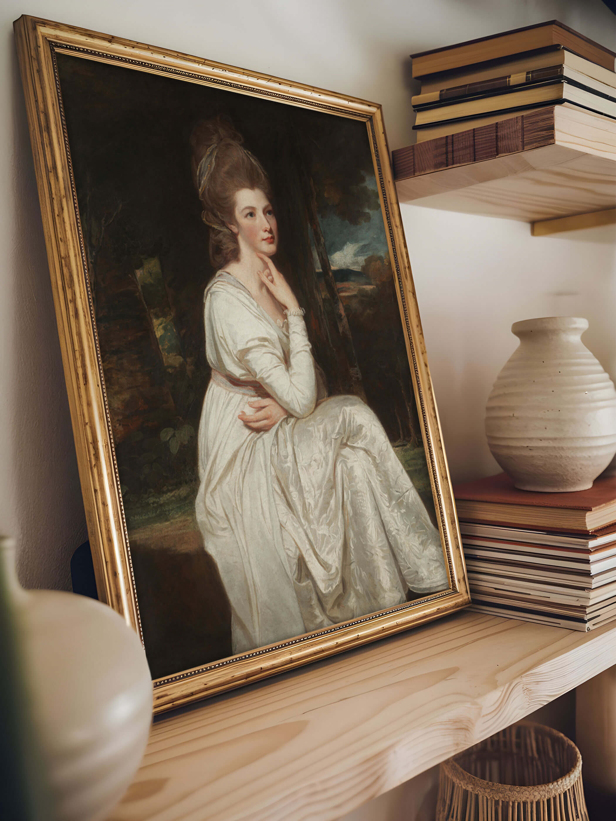 Vintage-Porträt einer Frau in einem goldenen Rahmen, auf einem Regal neben dekorativen Büchern und einer Keramikvase ausgestellt. Das Bild zeigt Lady Elizabeth Stanley in einem weißen Kleid.