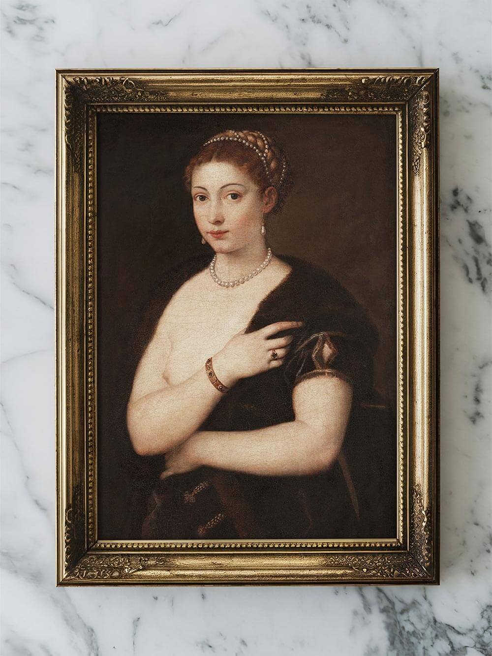 Renaissance-Porträt einer Frau mit Perlenkette und goldgerahmtem Kunstdruck auf hellem Marmortisch. Elegante, zeitlose Darstellung für klassische oder moderne Raumdekoration.