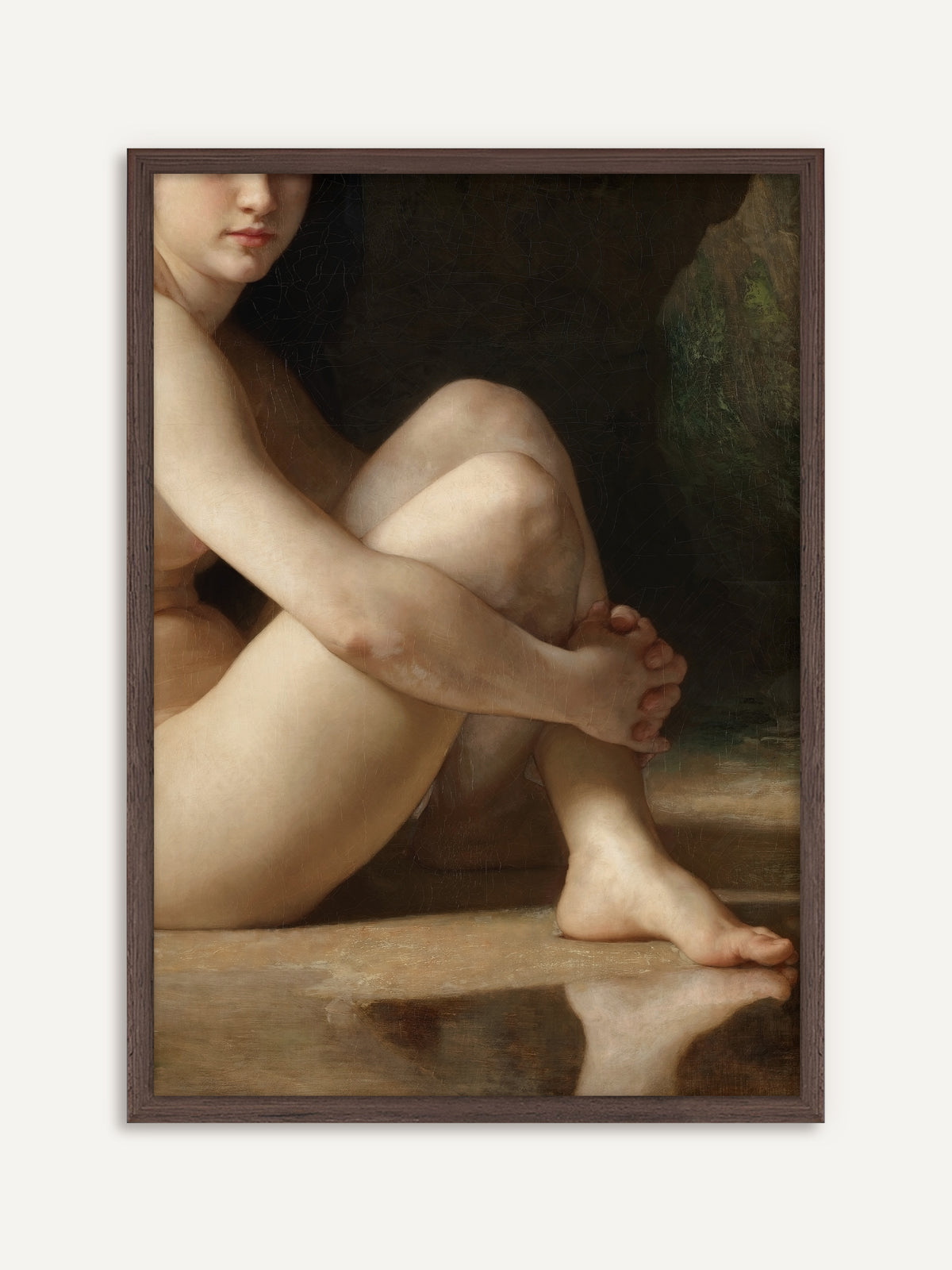 Eine nackte Frau sitzt mit angezogenen Knien am Wasser und umfasst ihr Schienbein, ihr Fuß spiegelt sich in der glatten Wasserfläche, dahinter dunkler Fels. Der Rahmen aus dunklem Holz unterstreicht die moody Stimmung dieses gerahmten Posters. #Rahmen_Dunkles Holz