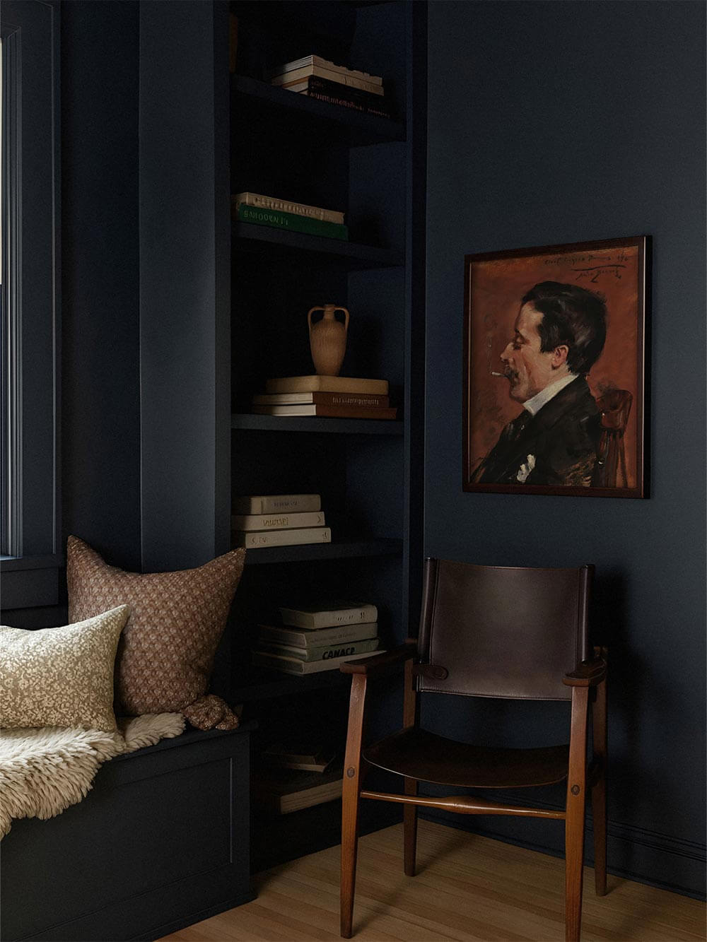 Vintage-Porträt eines rauchenden Mannes in dunklem Rahmen an marineblauer Wand mit Ledersessel. Die stimmungsvolle Farbpalette verleiht dem Raum Tiefe und kultivierte Ruhe.