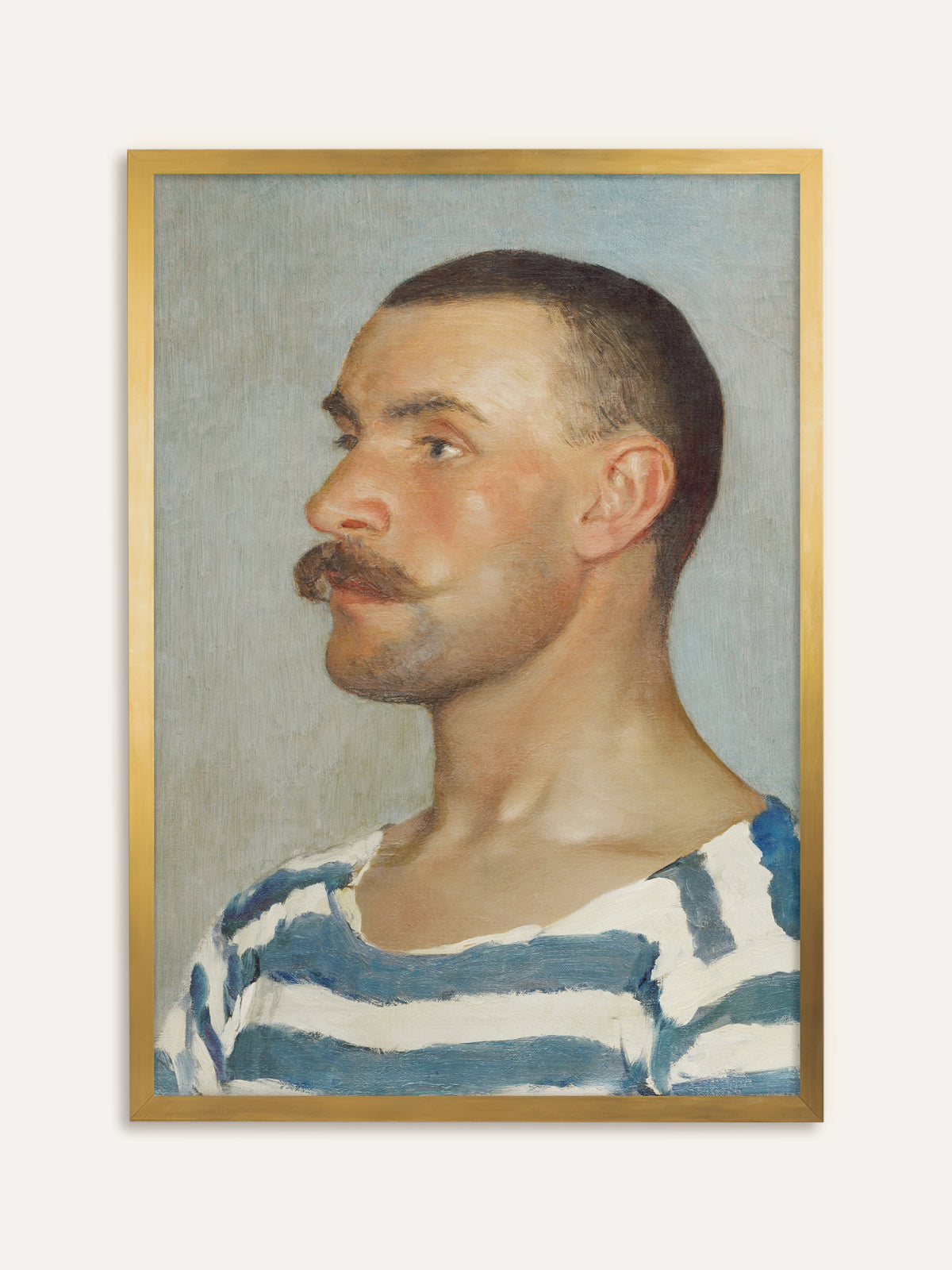 Wandbild, das einen Mann mit kurz geschorenem Haar und kräftigem Schnurrbart im Profil zeigt, in blau-weiß gestreiftem Shirt vor hellem, graublauem Hintergrund. Im goldenen Rahmen greift das Bild die warmen Hauttöne auf und wirkt wie ein klassisches Ölgemälde. #Rahmen_Gold