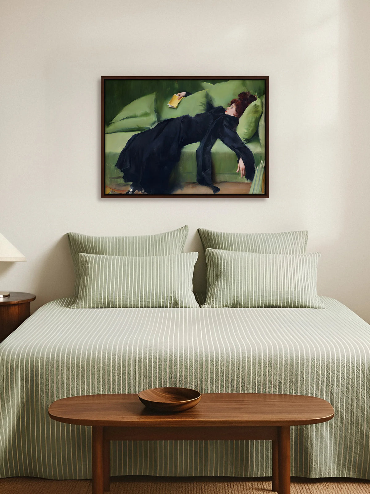 Leinwandbild mit junger Frau auf grünem Sofa im braunen Rahmen über einem Bett mit grün gestreifter Bettwäsche im Schlafzimmer
