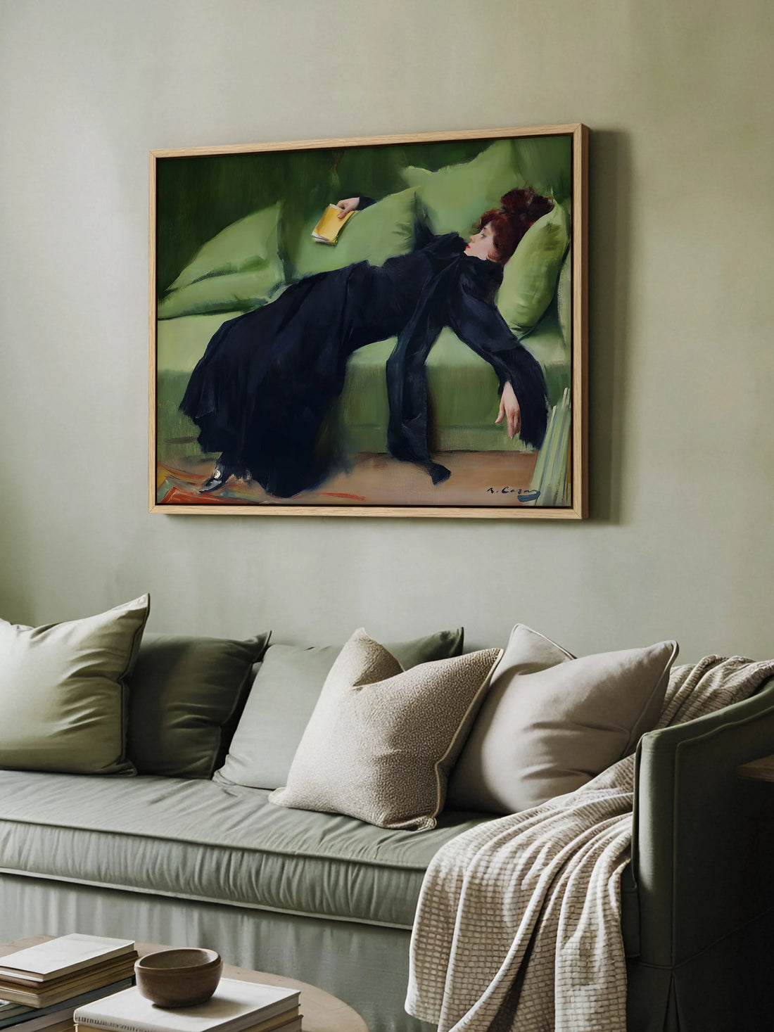Gerahmtes Leinwandbild einer jungen Frau in Schwarz auf grünem Sofa über einem salbeigrünen Sofa mit Kissen in Grün und Beige im Wohnzimmer
