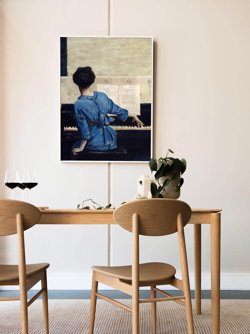 Kunstdruck einer Frau am Klavier in hell eingerichteter Esszimmerszene mit Holzstühlen und modernem Stil. Harmonische Wandkunst, die klassische Motive in zeitgenössisches Interior einfügt.