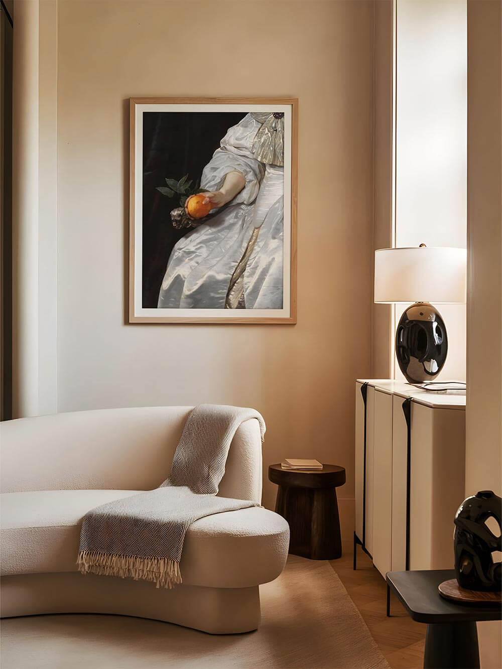 Barock-Kunstdruck mit einer edlen Hand, die eine Orange hält, stilvoll gerahmt und in einem modernen Wohnzimmer präsentiert. Die dunkle Farbpalette und der luxuriöse Stoff des Gemäldes schaffen eine elegante, kunstvolle Atmosphäre.

