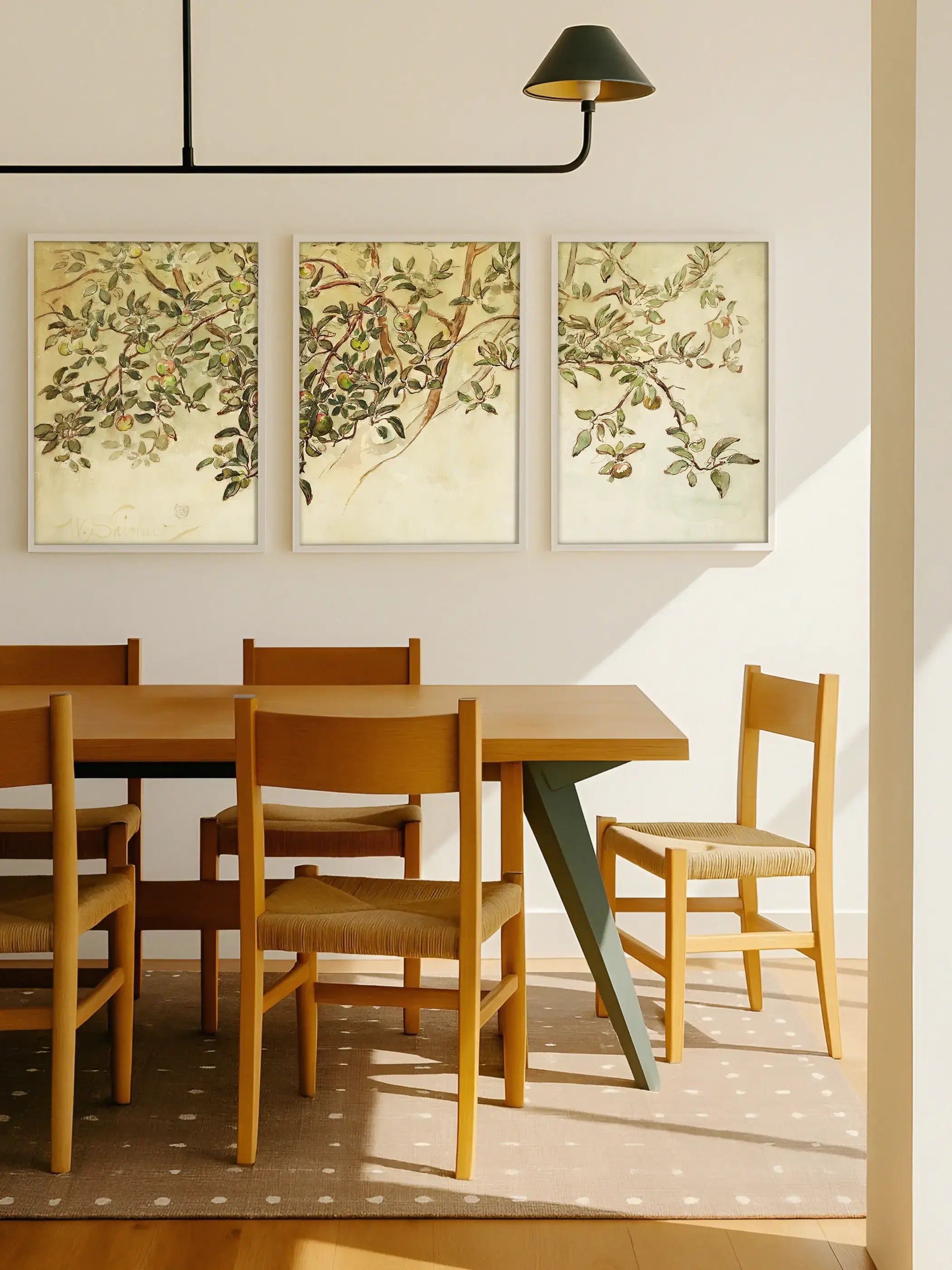 Das dreiteilige Apfelzweig Wandbild hängt über einem Esstisch aus Holz und ergänzt den hellen Raum mit natürlichen Farben. Die botanischen Poster verleihen dem Esszimmer eine ruhige und zeitlose Atmosphäre.