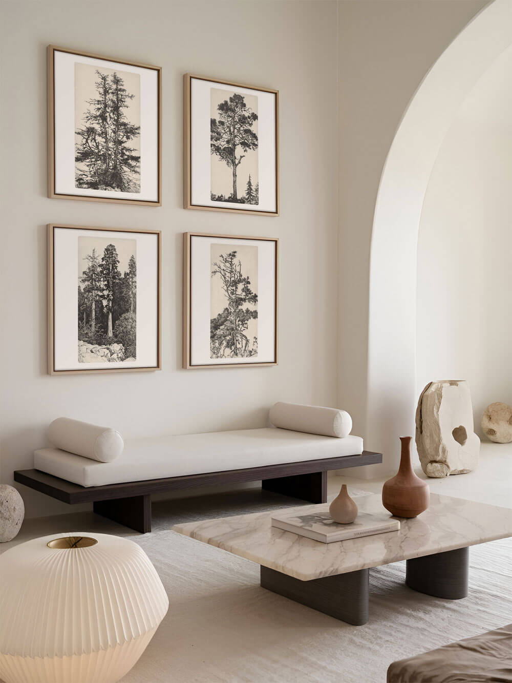 Vier gerahmte Vintage-Baumzeichnungen, die in einem modernen Wohnzimmer über einem minimalistischen Tagesbett und einem Marmortisch hängen und eine ruhige, elegante Atmosphäre schaffen.