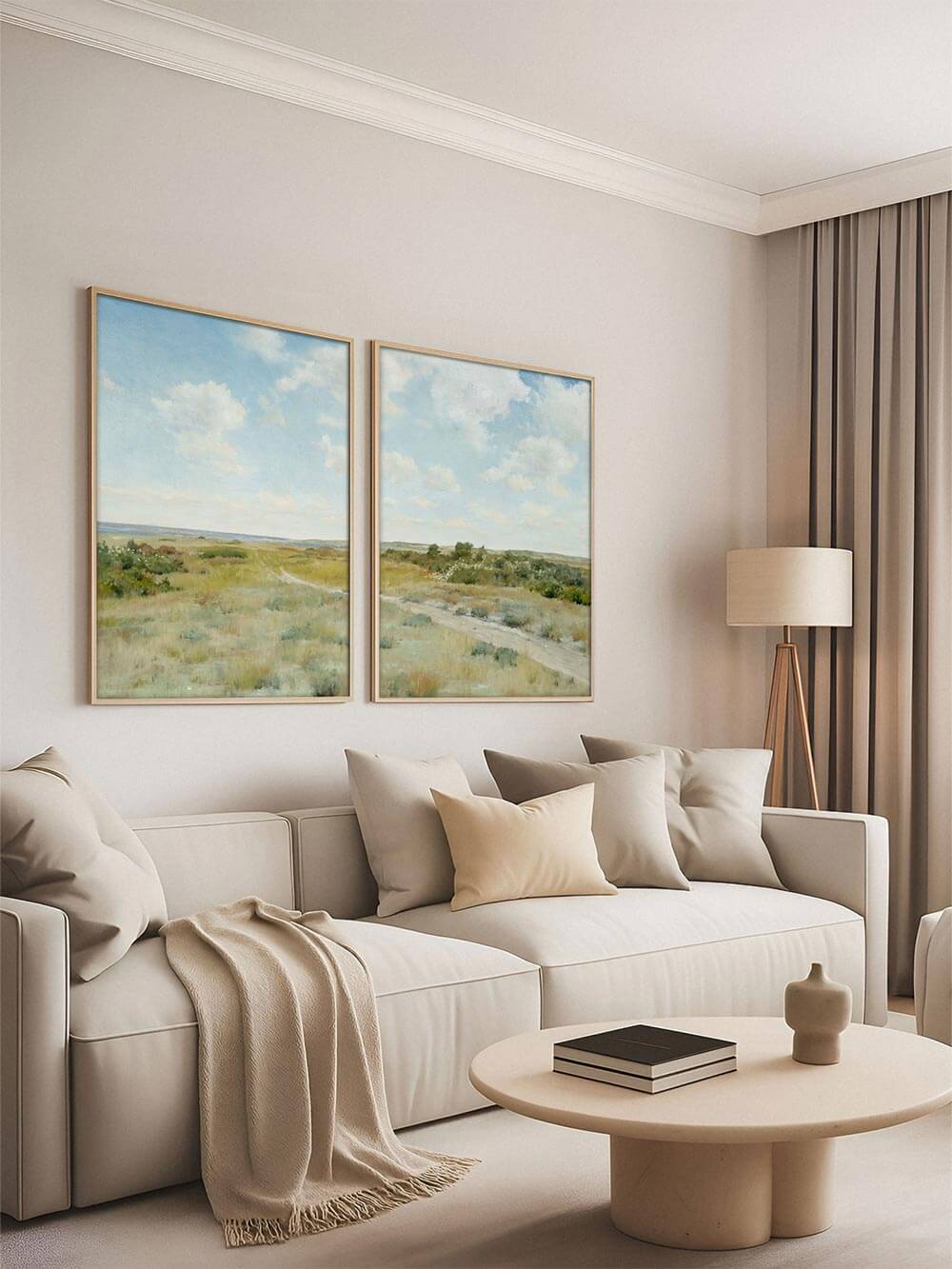 Zwei Landschafts-Kunstdrucke über beigem Sofa mit Kissen in Naturtönen. Die hellen Farben und der weite Horizont bringen Ruhe und Weite in ein minimalistisches Wohnzimmer im modernen Landhausstil.