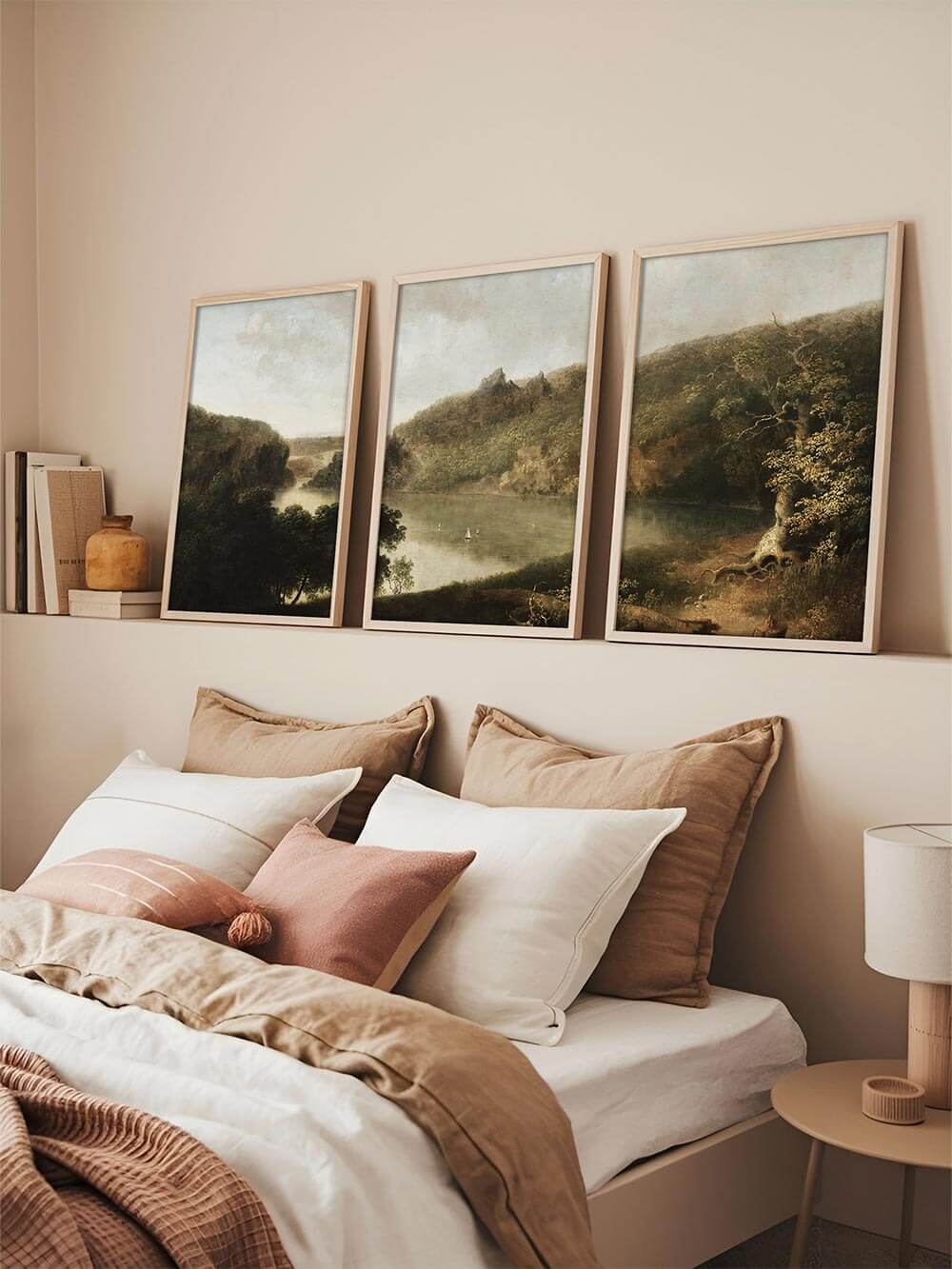 Dreiteiliges Landschafts-Triptychon lehnt über einem Bett mit neutraler Bettwäsche, die ruhige Flusslandschaft und sanfte Grüntöne schaffen eine entspannte Atmosphäre und machen das Poster-Set zu einem eleganten Wandbild für das Schlafzimmer.