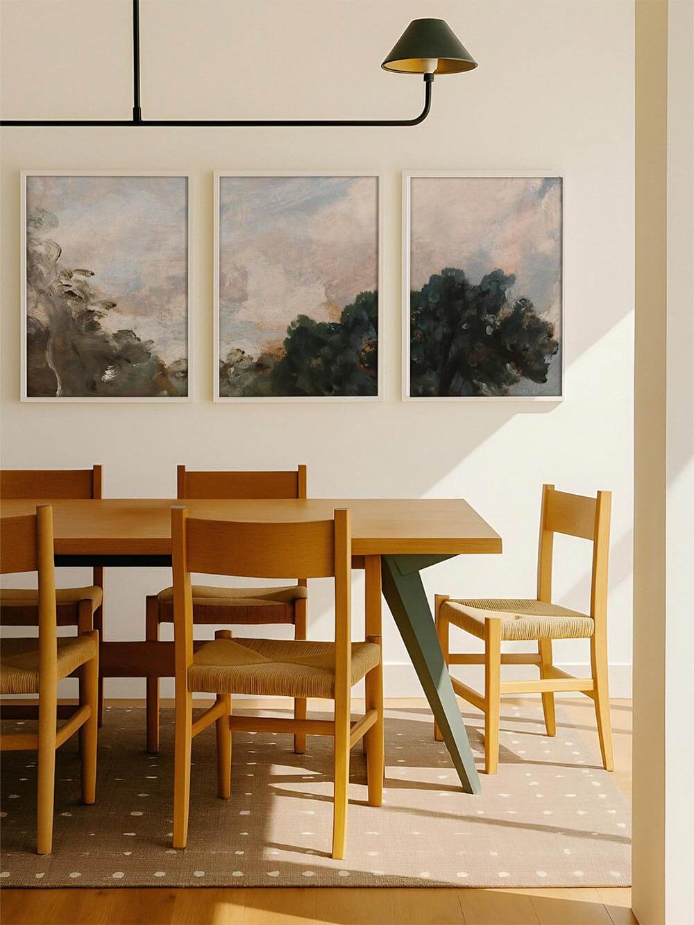 Dreiteiliges Wandbild als Galerie-Wand über einem Esstisch mit hellen Holzmöbeln und moderner Leuchte. Die abstrakten Landschaftsmotive fügen sich ruhig in den Raum ein und verleihen dem Esszimmer eine warme, zeitlose Atmosphäre.