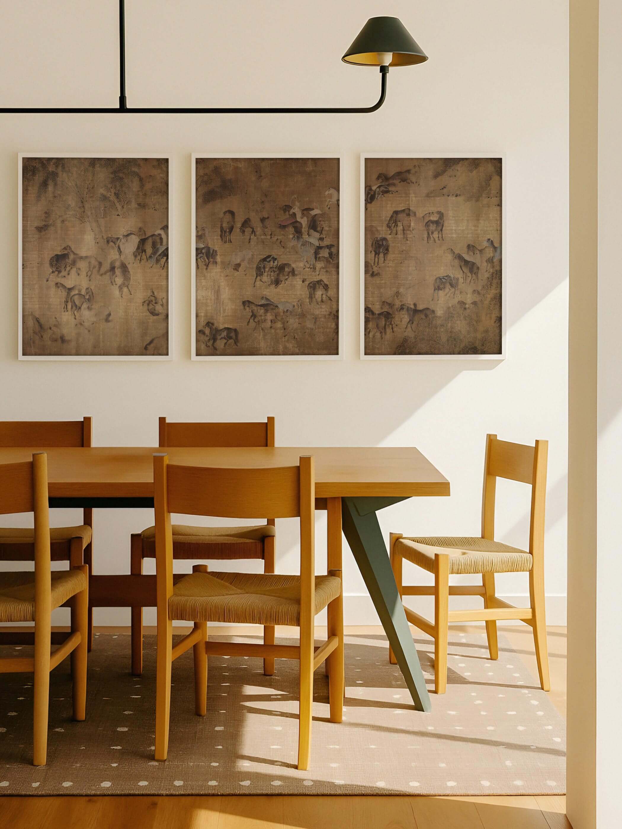 Drei gerahmte Poster mit filigranen Pferdedarstellungen in gedeckten Braun- und Beigetönen hängen über einem Holztisch im Esszimmer. Das Triptychon ergänzt das warme Interieur und wirkt als stilvolle, ruhige Galerie-Wand.