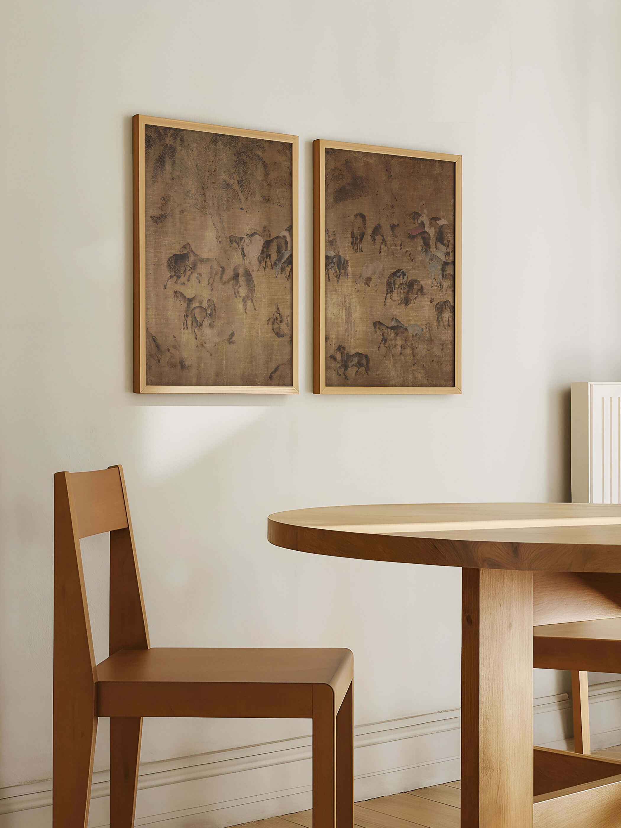 Zwei gerahmte Poster mit filigranen Pferdedarstellungen in warmen Naturtönen hängen über einem Holztisch im Essbereich. Das Set fügt sich harmonisch in das minimalistische Interieur ein und wirkt als stilvolle, ruhige Wandgestaltung.