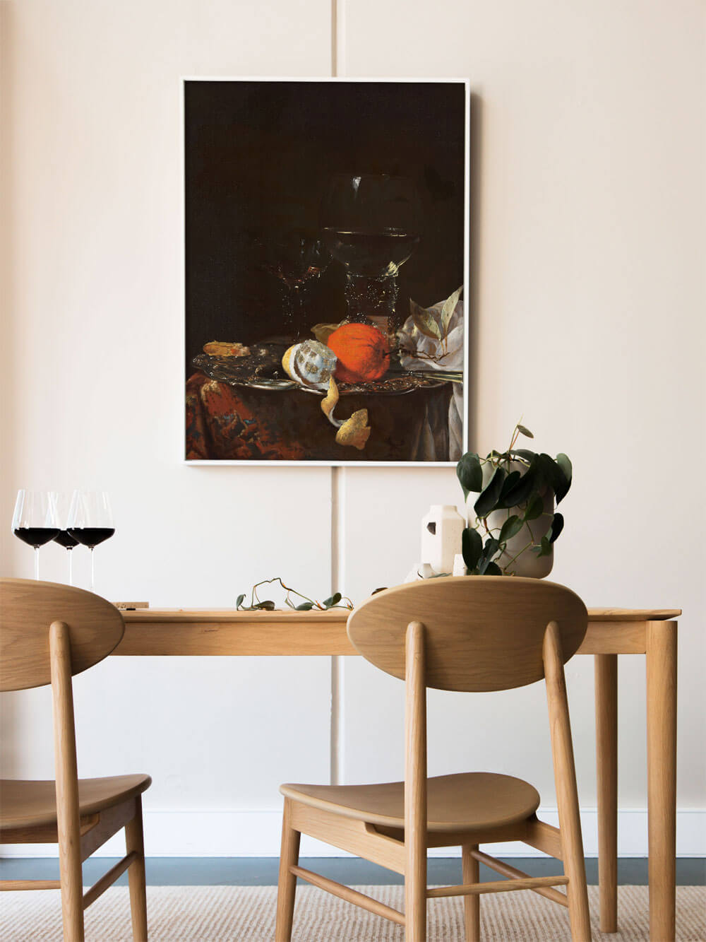 Barockes Stillleben-Kunstdruck mit Orangen und Zitronen auf einem Silbertablett, eingerahmt über einem minimalistischen Holztisch mit zwei Weingläsern.