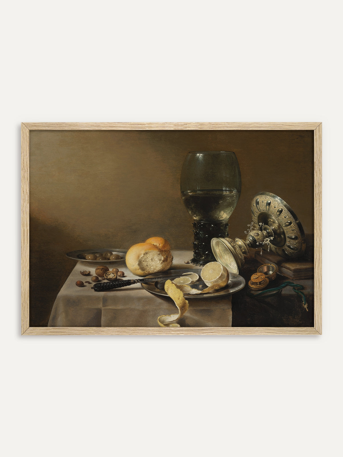 Kunstdruck, der einen Römer mit Weißwein, eine umgekippte silberne Tazza, eine halb geschälte Zitrone auf einem Zinnteller, ein Brötchen, Nüsse und Oliven auf einem weiß gedeckten Tisch vor warmem Braun zeigt. Im Rahmen aus hellem Holz wirkt das barocke Stillleben ruhig und hell. #Rahmen_Helles Holz