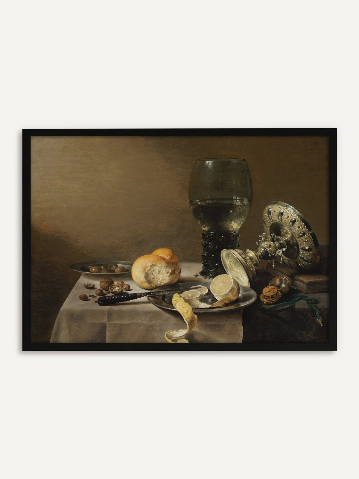 Gerahmtes Poster, das einen Römer mit Weißwein, eine umgekippte silberne Tazza, eine halb geschälte Zitrone auf einem Zinnteller, ein Brötchen, Nüsse und Oliven auf einem weiß gedeckten Tisch vor warmem Braun zeigt. Mit schwarzem Rahmen wird das monochrome Vintage-Stillleben klar und modern. #Rahmen_Schwarz