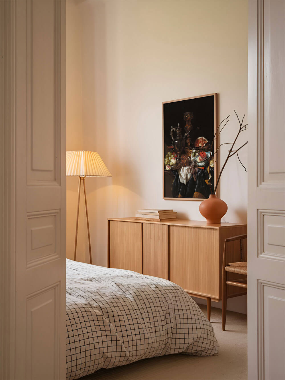 Barockes Stillleben, dunkel gehalten, mit silbernem Krug und Früchten, an der Wand eines gemütlichen Schlafzimmers über einer Kommode mit einer Vase arrangiert.