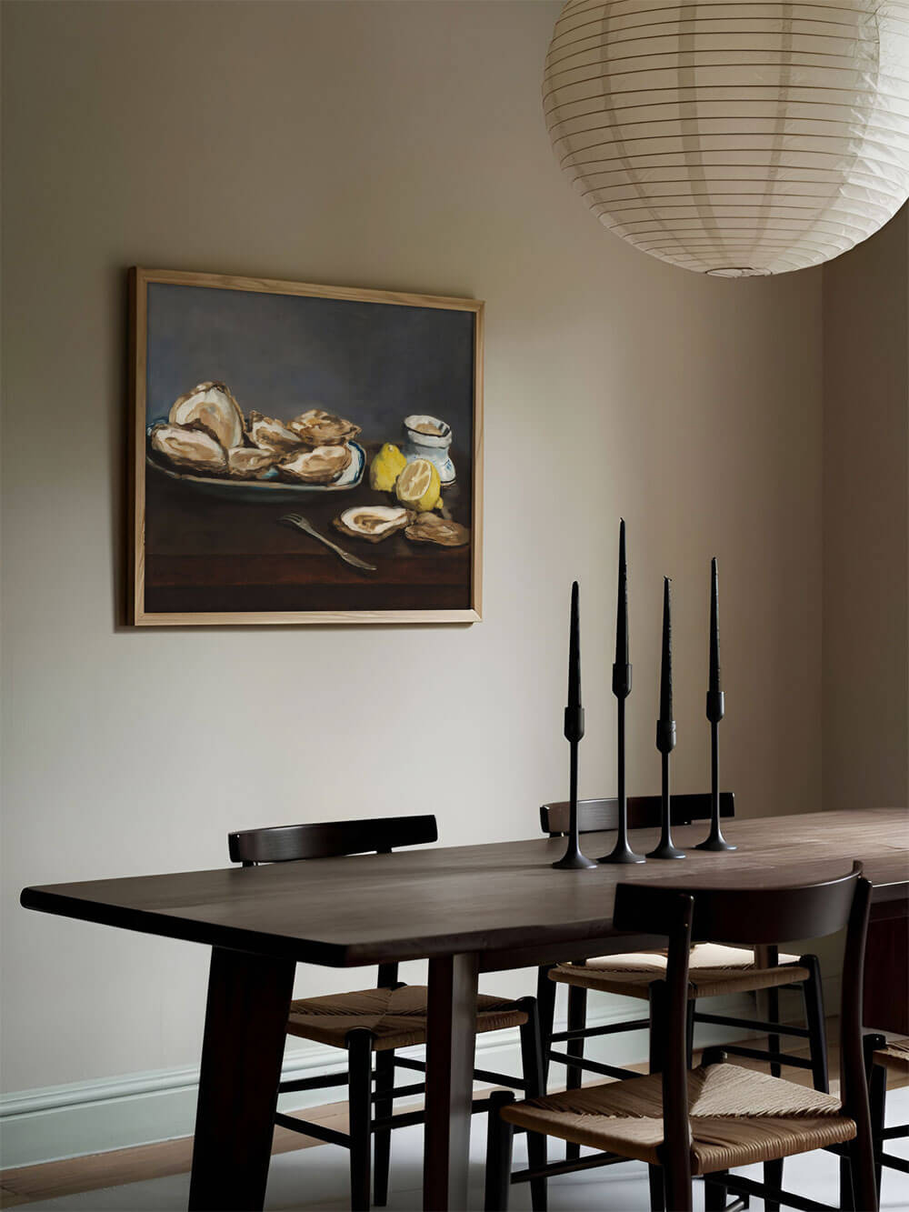 Ein Austern-Stillleben-Kunstdruck in einem minimalistisch eingerichteten Esszimmer. Der Holzrahmen des Kunstwerks fügt sich nahtlos in die warme, natürliche Einrichtung ein und verleiht dem Raum eine rustikale Eleganz.