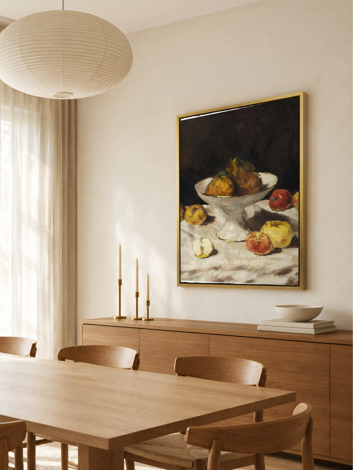 Leinwandbild mit Obstschale im goldenen Rahmen über einem Sideboard aus Eiche mit Messingleuchtern im hellen Esszimmer mit Papierleuchte