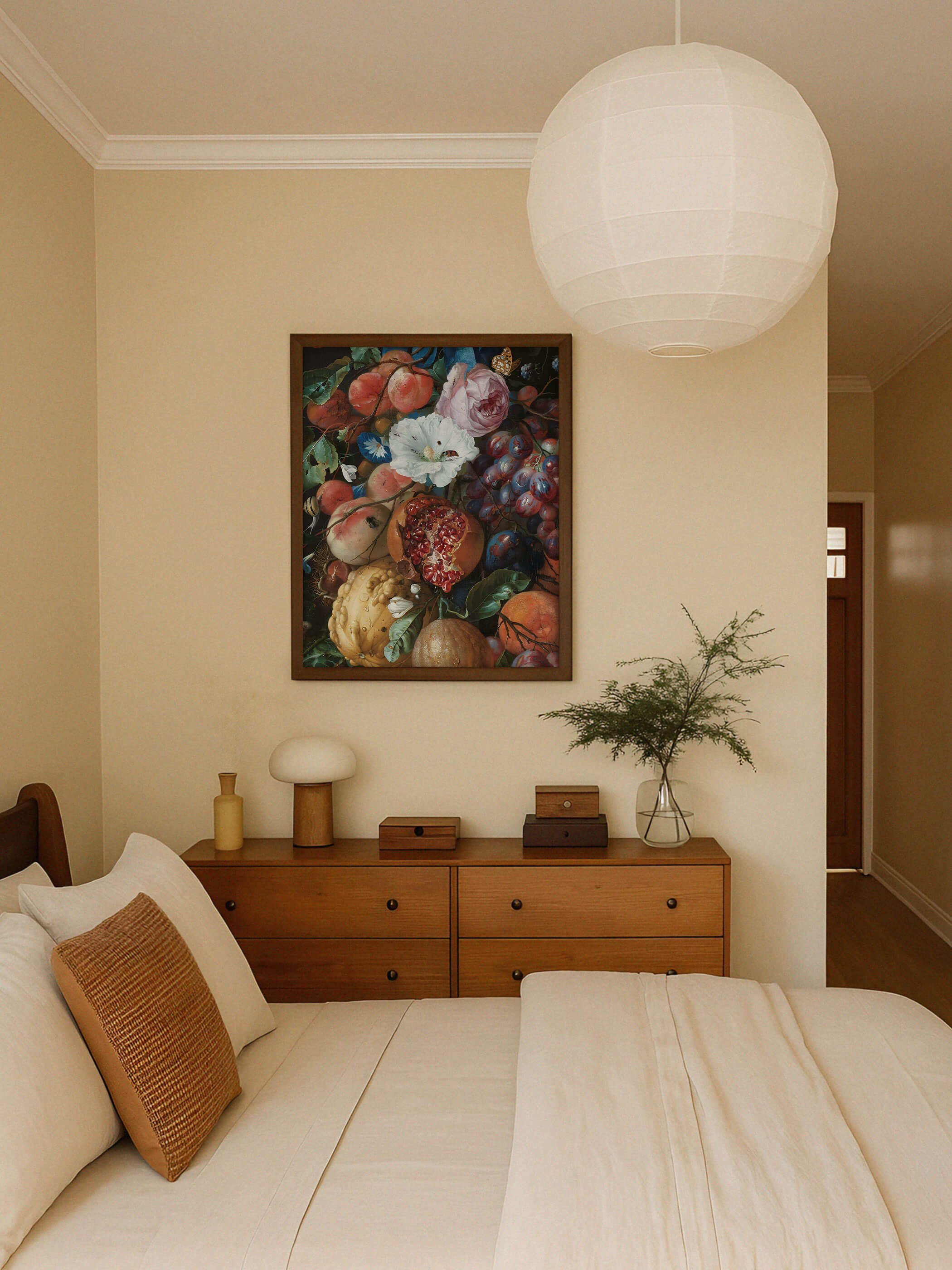 Dunkel gerahmter Kunstdruck mit barocker Früchte- und Blumengirlande hängt über einer Holzkommode in einem warmen, beigen Schlafzimmer. Das farbenprächtige Motiv setzt einen opulenten Akzent neben Nachttischlampe und Vase.