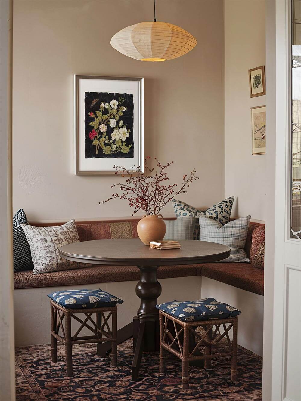 Vintage-Blumenposter in stilvoll eingerichteter Essnische. Der Kunstdruck mit floraler Stickerei auf dunklem Hintergrund harmoniert mit der warmen Farbpalette des Raumes und verleiht ihm eine zeitlose Eleganz.