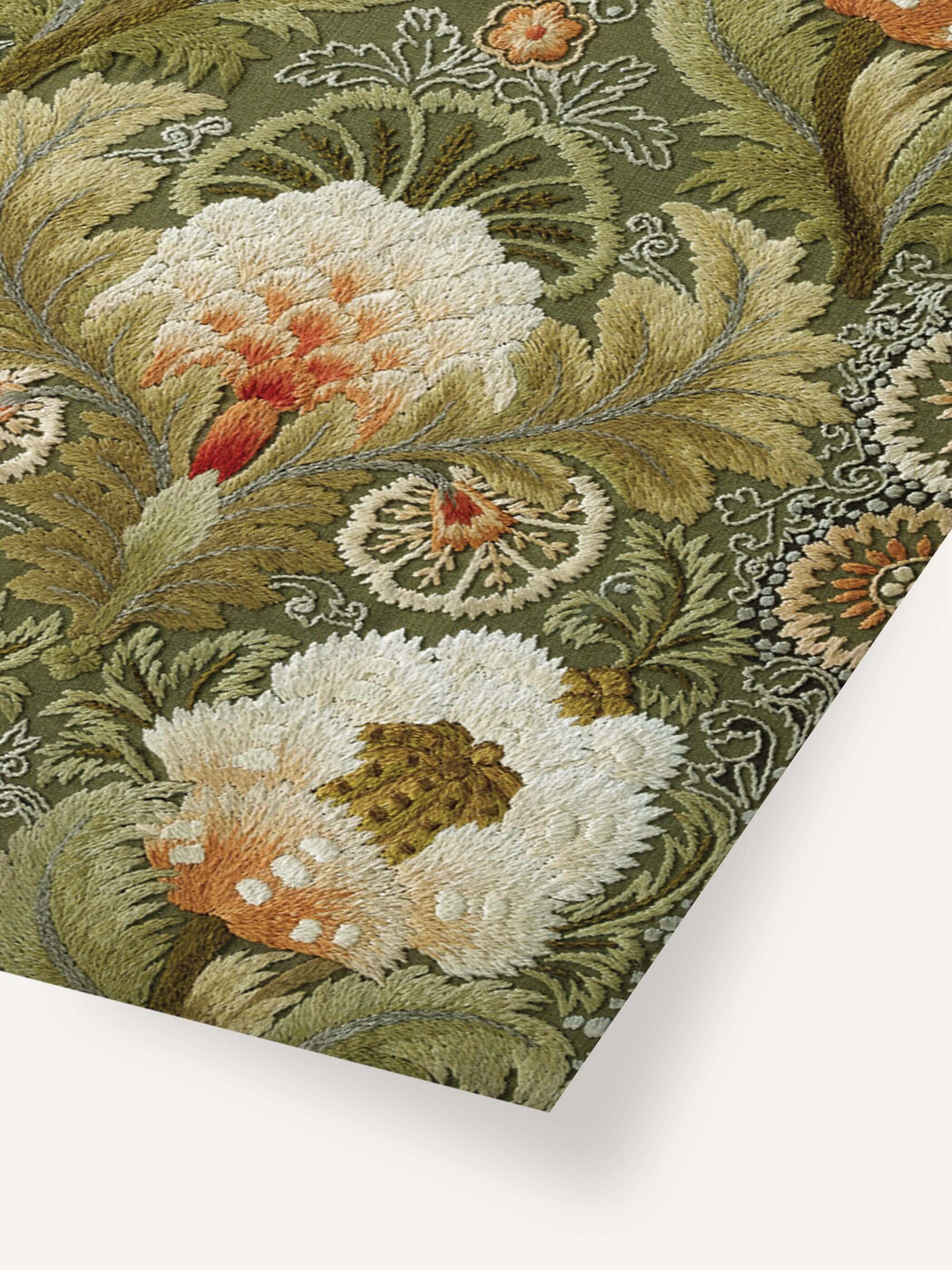 Nahaufnahme eines Kunstdrucks mit detailreicher Seidenstickerei, die große, weiße Blumen mit orangen Akzenten und grünen Blättern zeigt.
