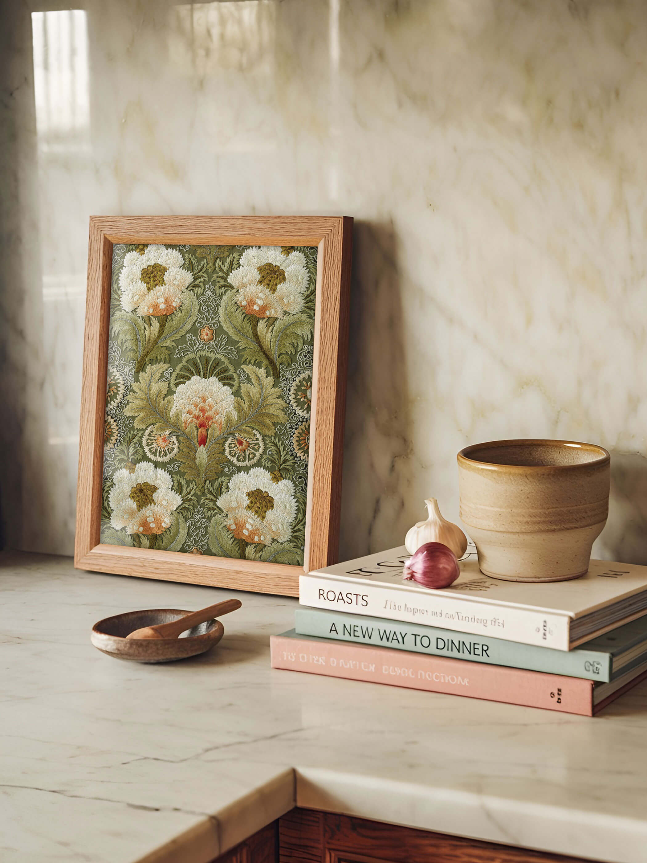 Vintage Stickerei Kunstdruck in einem Holzrahmen, dekorativ auf einer Marmorplatte präsentiert, umgeben von Kochbüchern und Küchenaccessoires.