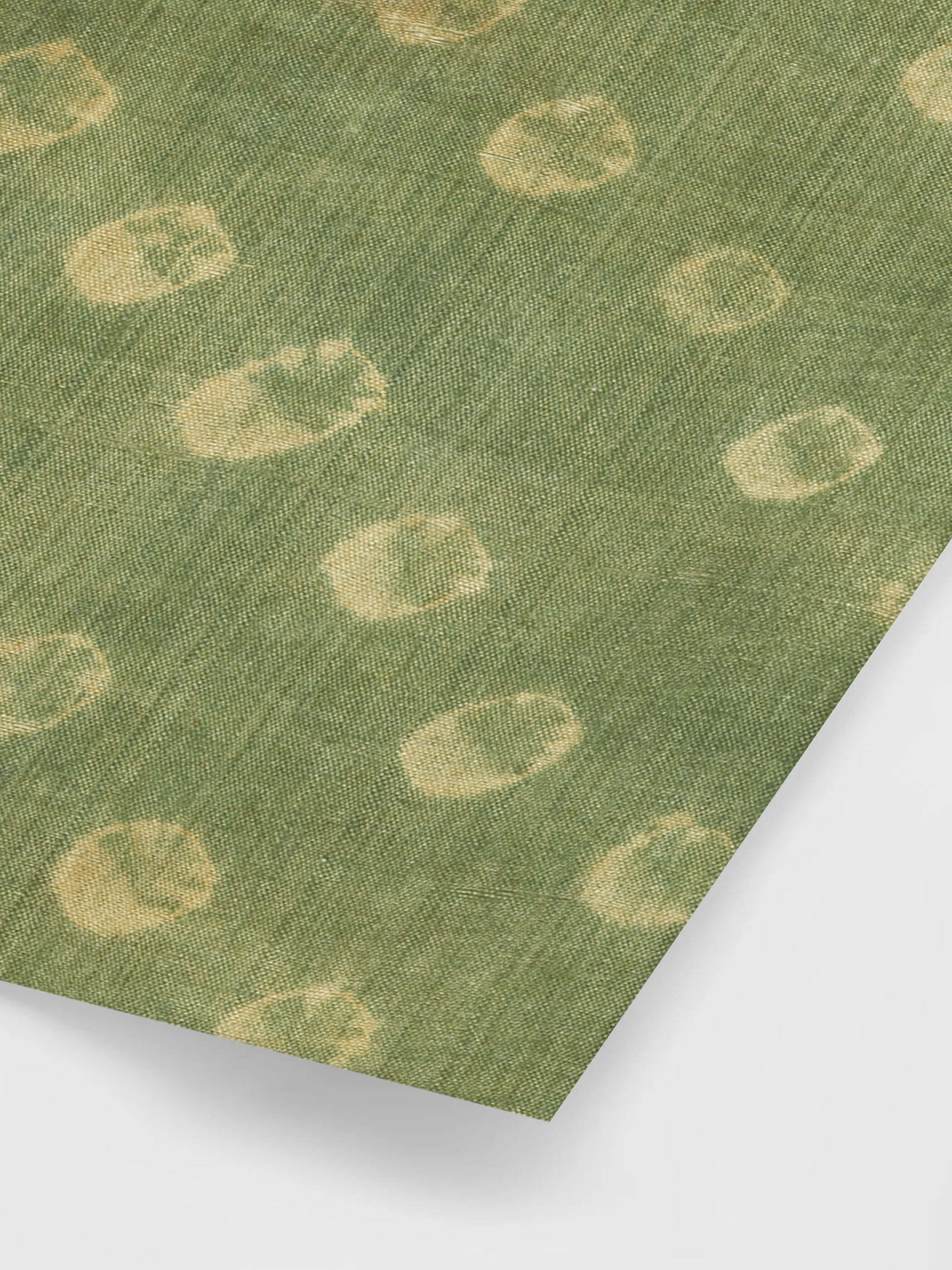 Nahaufnahme eines grünen Wabi-Sabi Posters mit beigen Kreismustern, die ein antikes Tabby-Gewebe-Fragment aus dem 7. Jahrhundert zeigen. Die Textur und Unregelmäßigkeiten der Stoffstruktur betonen den minimalistischen und rustikalen Charme im japanischen Wabi-Sabi-Stil.